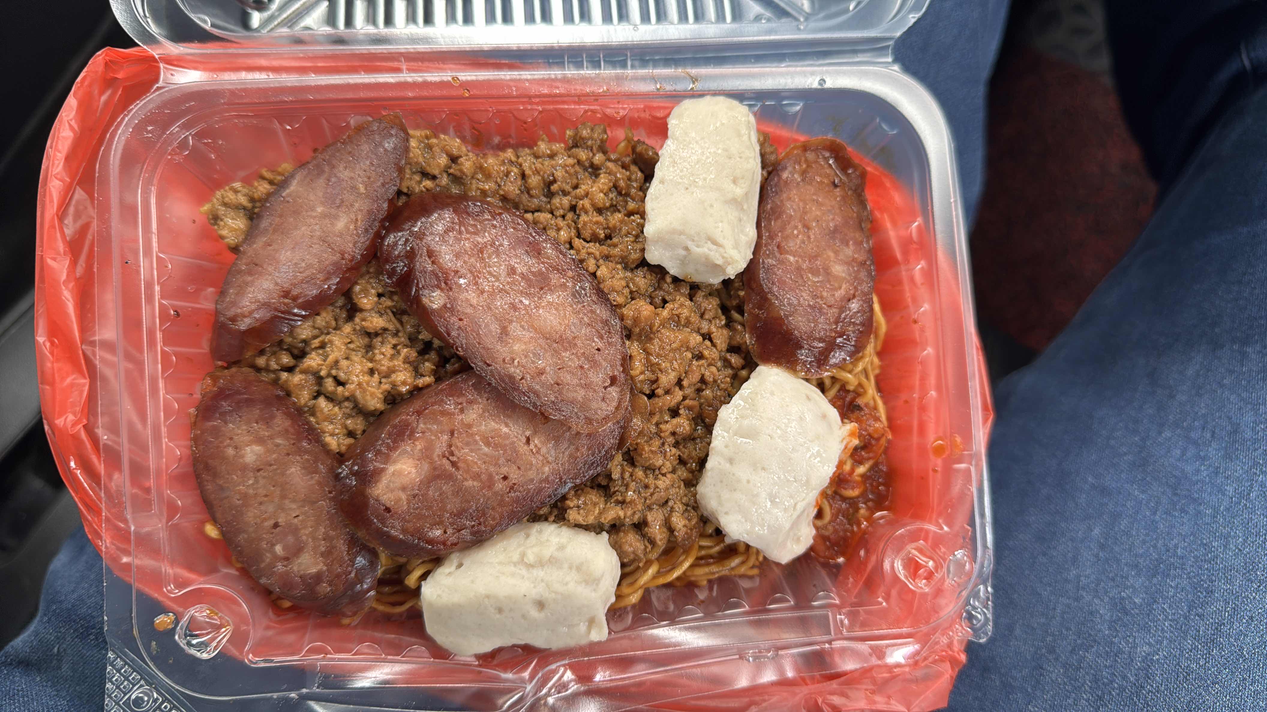 A high-calorie noodle dish topped with ground meat, Chinese sausage, and fish balls, providing a balanced mix of protein, fats, and carbohydrates.
