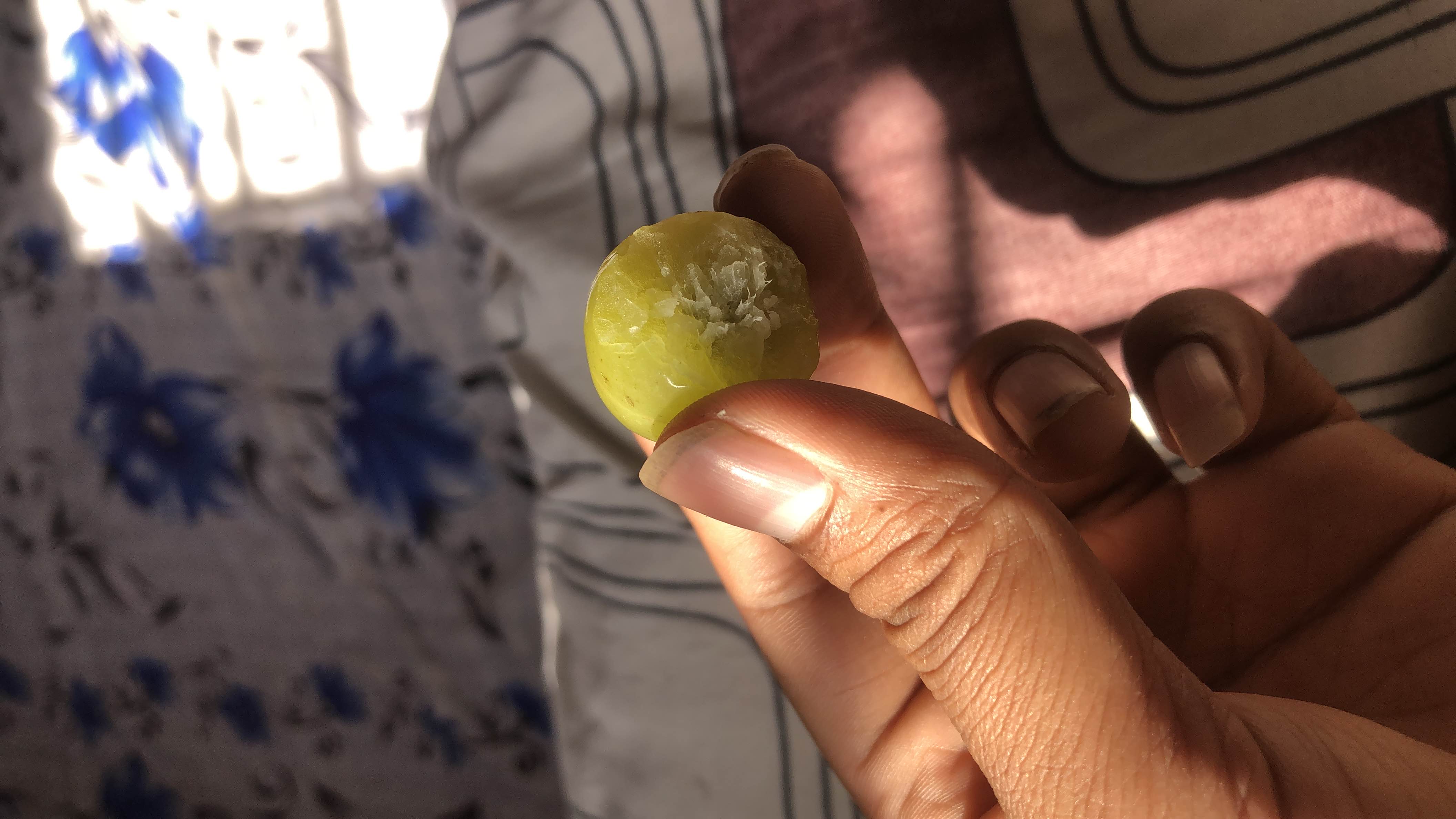 A single green grape, partially eaten, which is low in calories and rich in natural sugars and antioxidants.