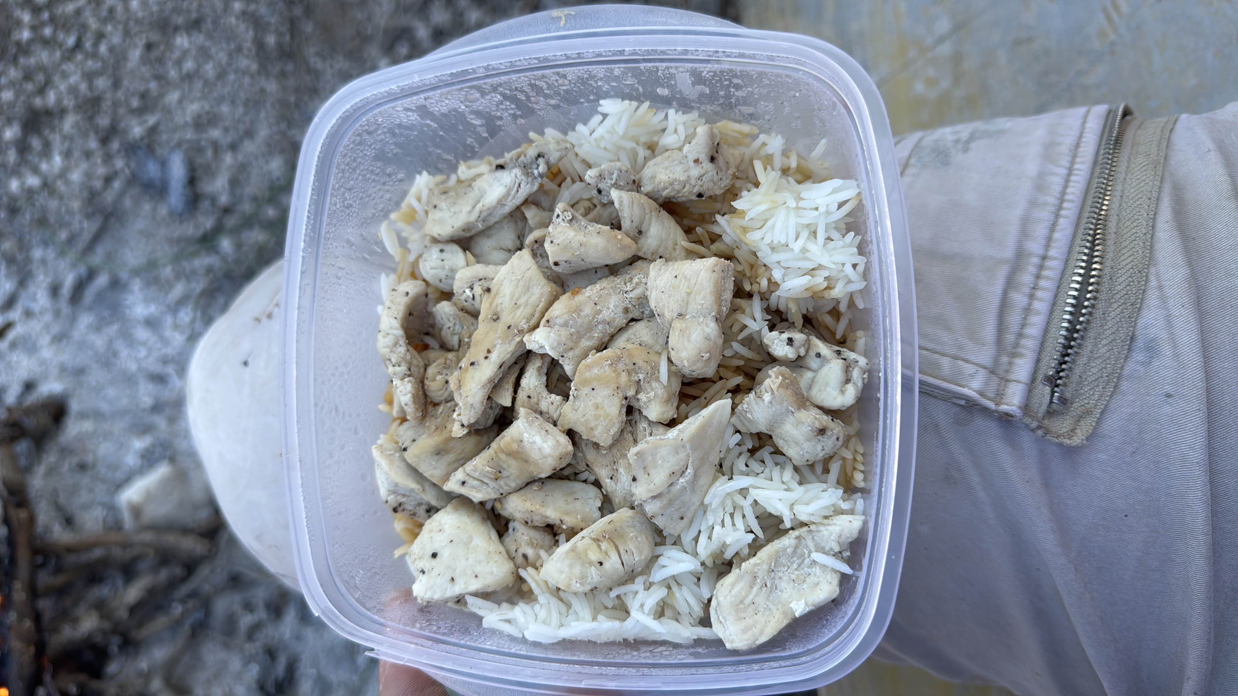 A high-protein meal consisting of grilled chicken breast and white rice, seasoned with black pepper.
