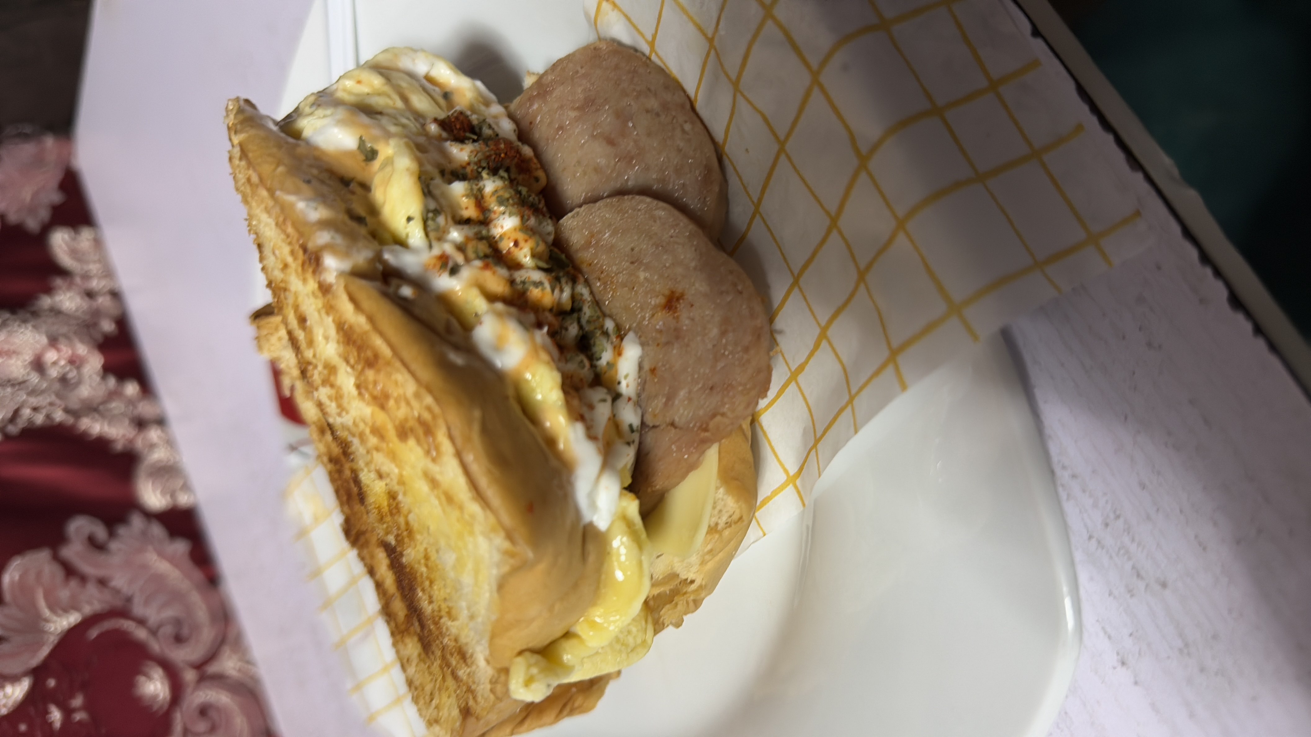 A high-calorie sandwich with bread, eggs, cheese, sausage, and sauce, offering a balanced mix of protein, fats, and carbohydrates.