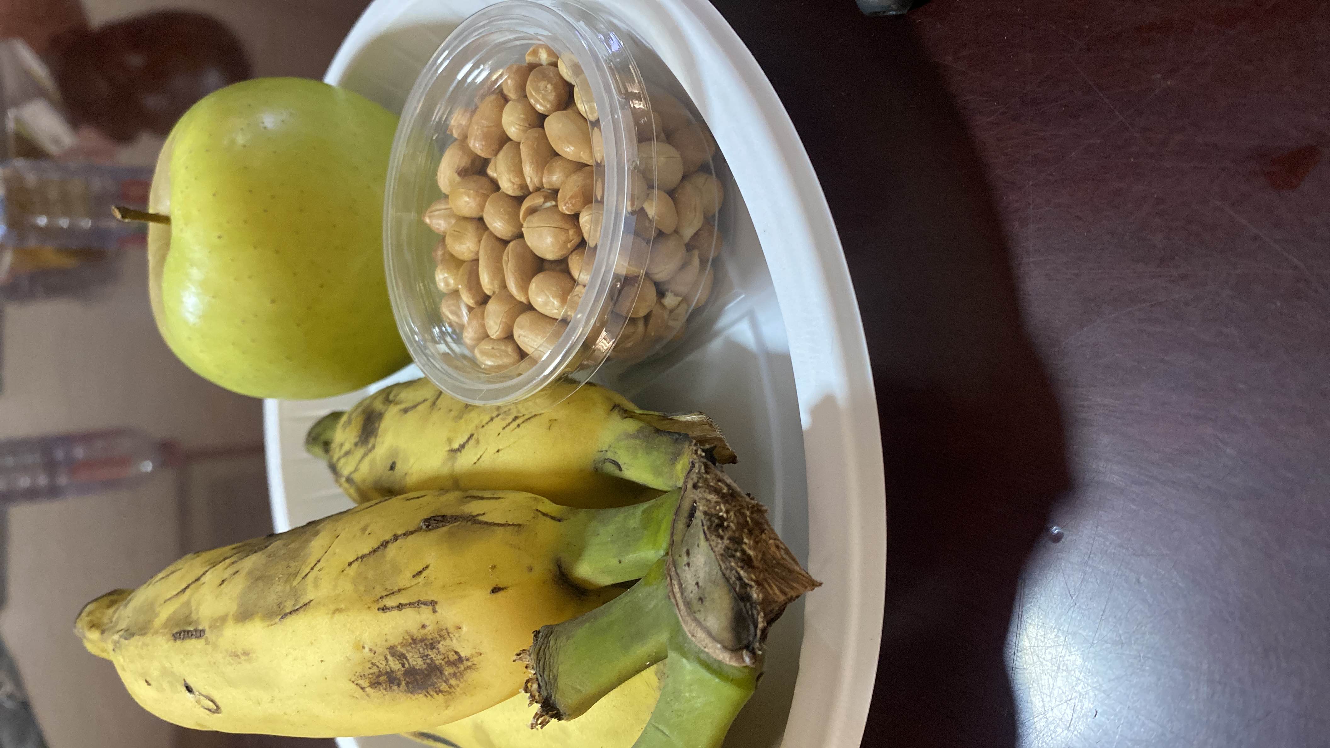 A healthy plate containing bananas, an apple, and a portion of peanuts, providing a balanced mix of carbohydrates, proteins, and fats.