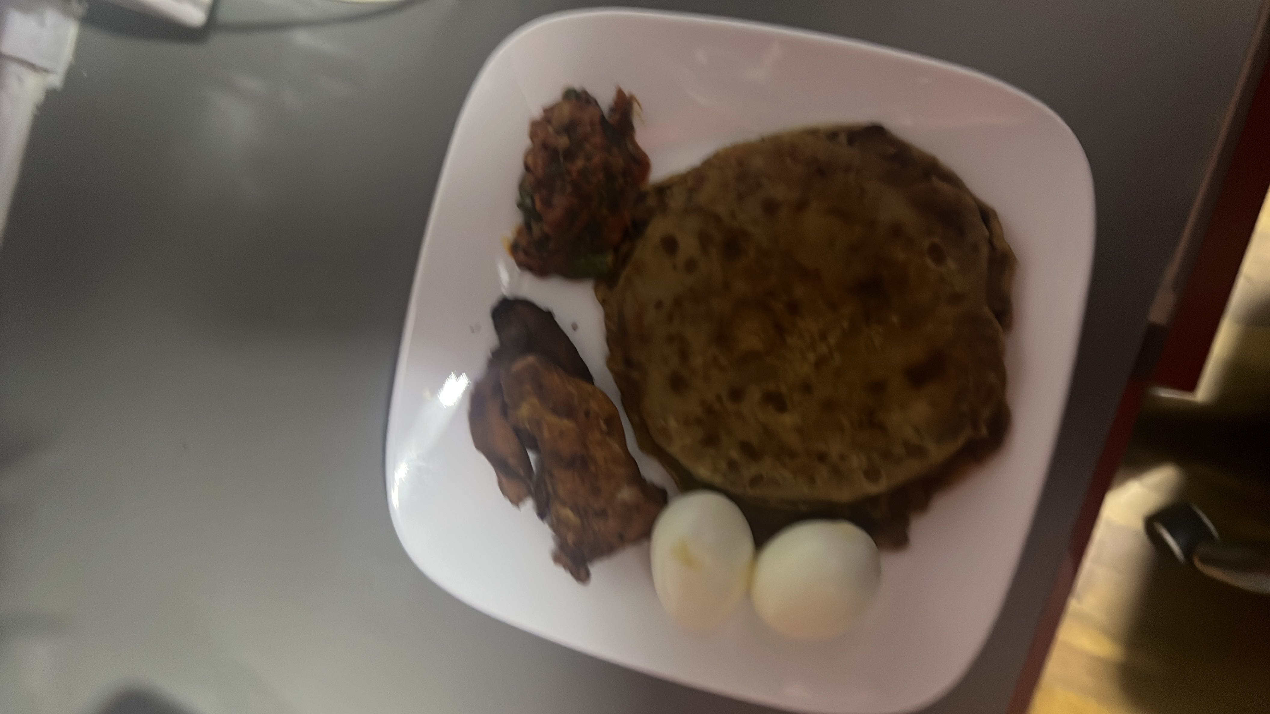 A balanced meal consisting of aloo paratha, boiled eggs, grilled chicken, vegetable curry, and tomato chutney, providing a good mix of protein, carbohydrates, and fats.