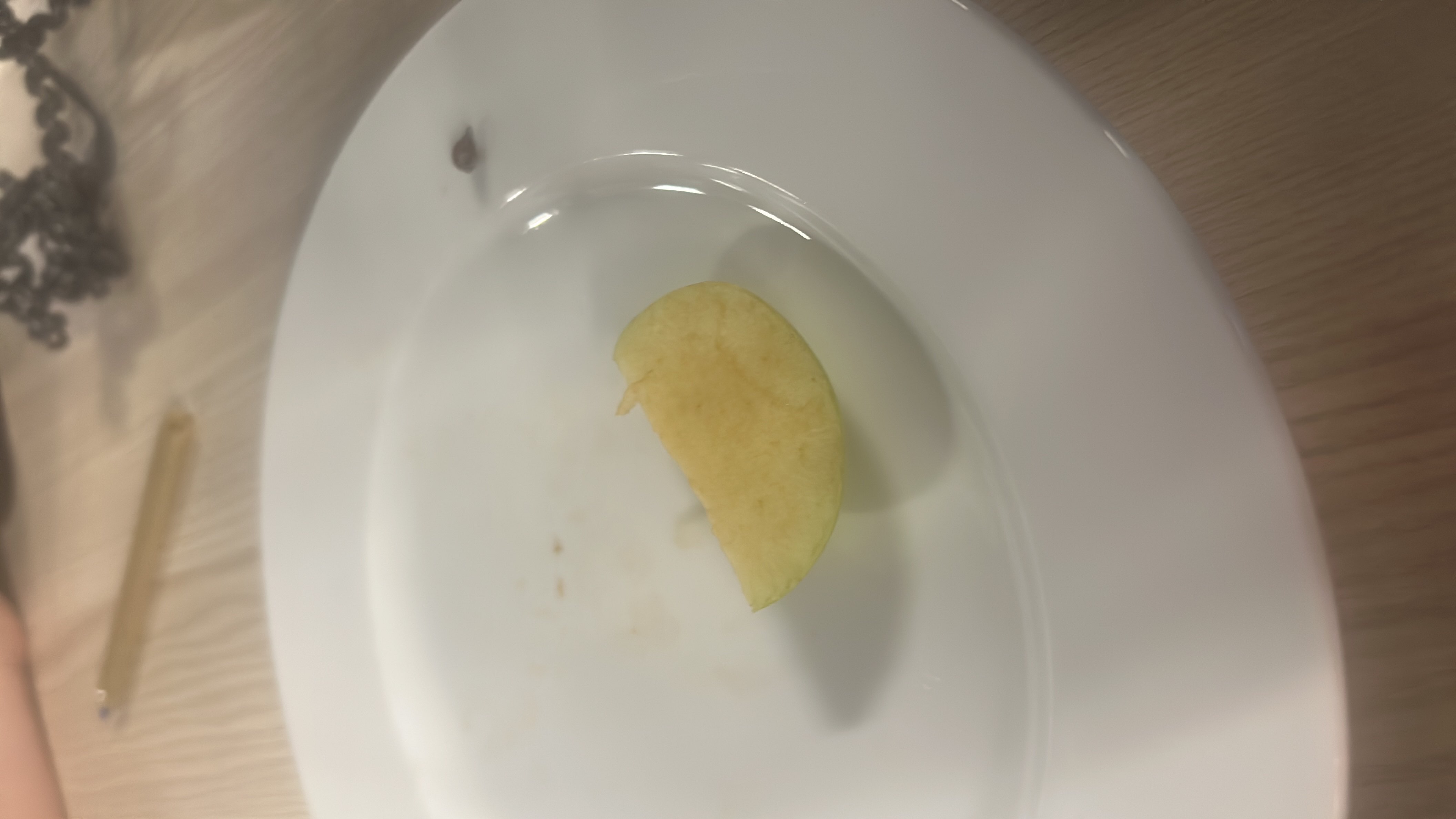 A single slice of apple on a white plate, providing a low-calorie and nutritious snack rich in carbohydrates.