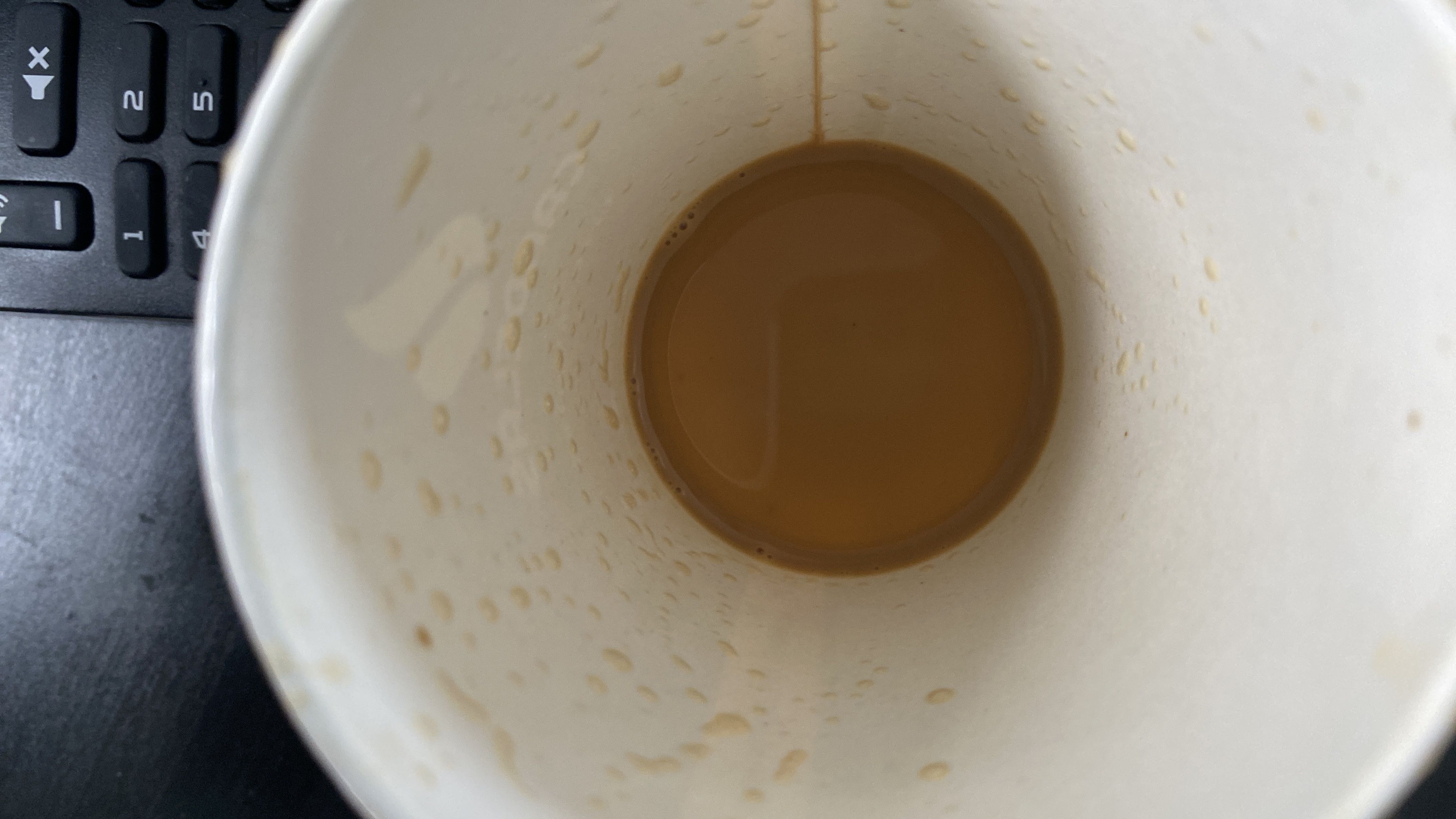 A partially consumed cup of coffee with milk and sugar, providing a low-calorie beverage with minimal protein and fats.