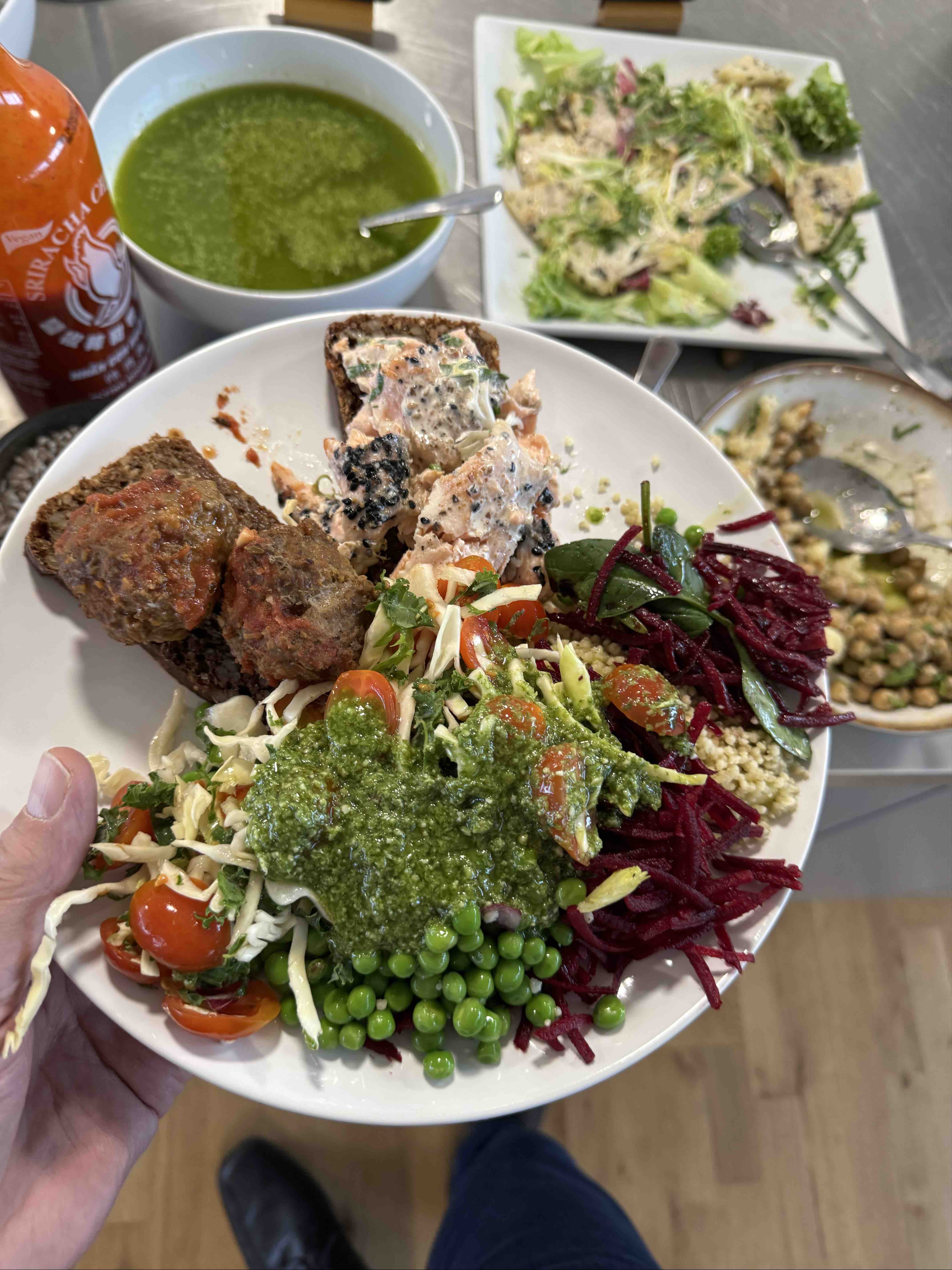 A nutritious meal featuring salmon, whole grain bread, fresh vegetables, quinoa, and pesto sauce, providing a balanced mix of protein, healthy fats, and carbohydrates.