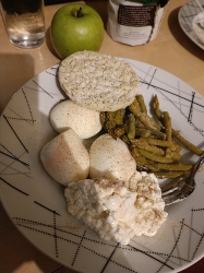 A balanced meal consisting of rice cakes, cottage cheese, boiled eggs, green beans, and an apple, providing a good mix of protein, carbs, and fats.