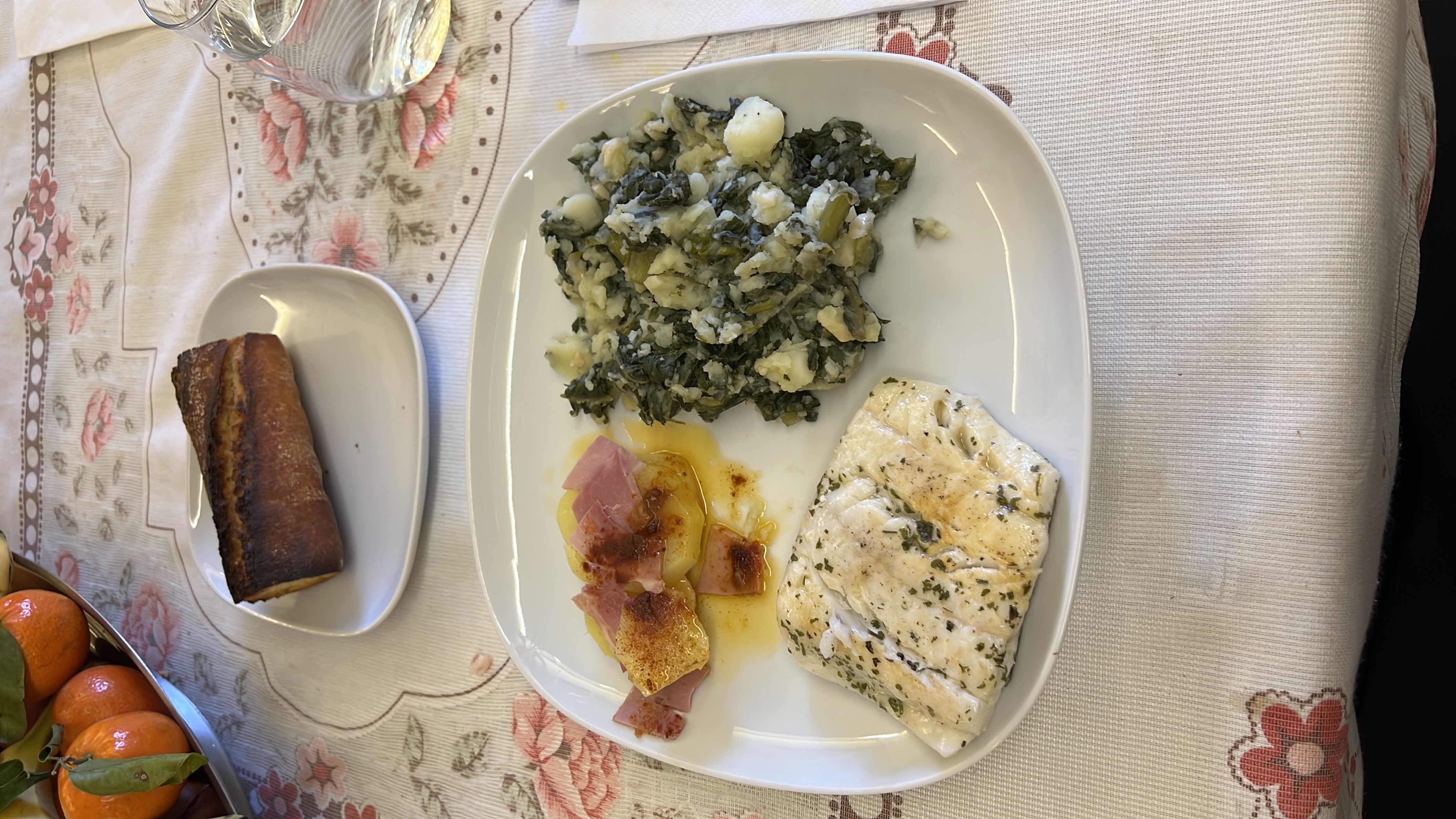 A balanced meal consisting of grilled fish, mashed potatoes with greens, potatoes with ham and oil, and a piece of bread, providing a good mix of protein, carbohydrates, and fats.