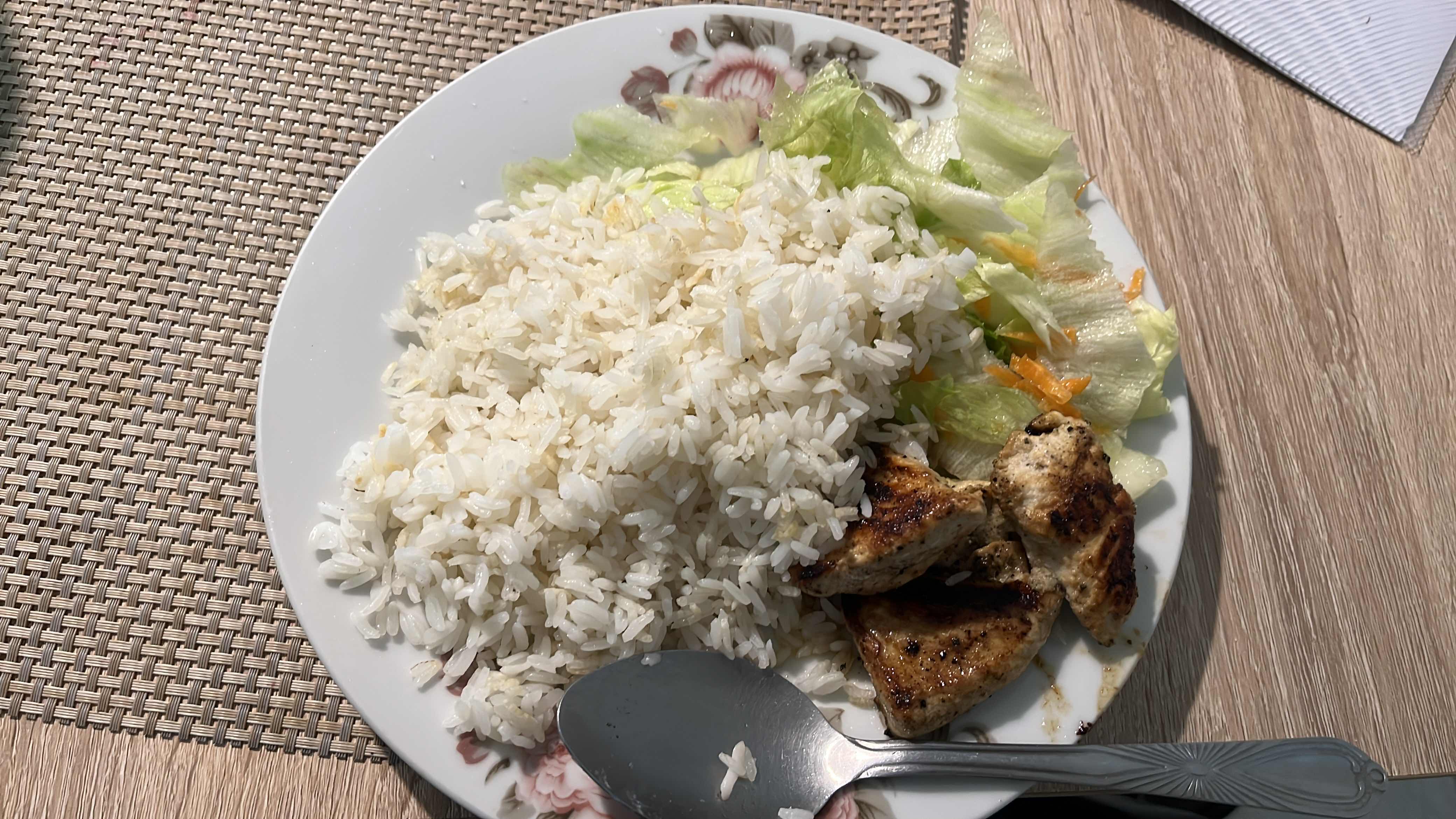 A balanced meal consisting of white rice, grilled chicken, and a fresh salad with lettuce and carrots.