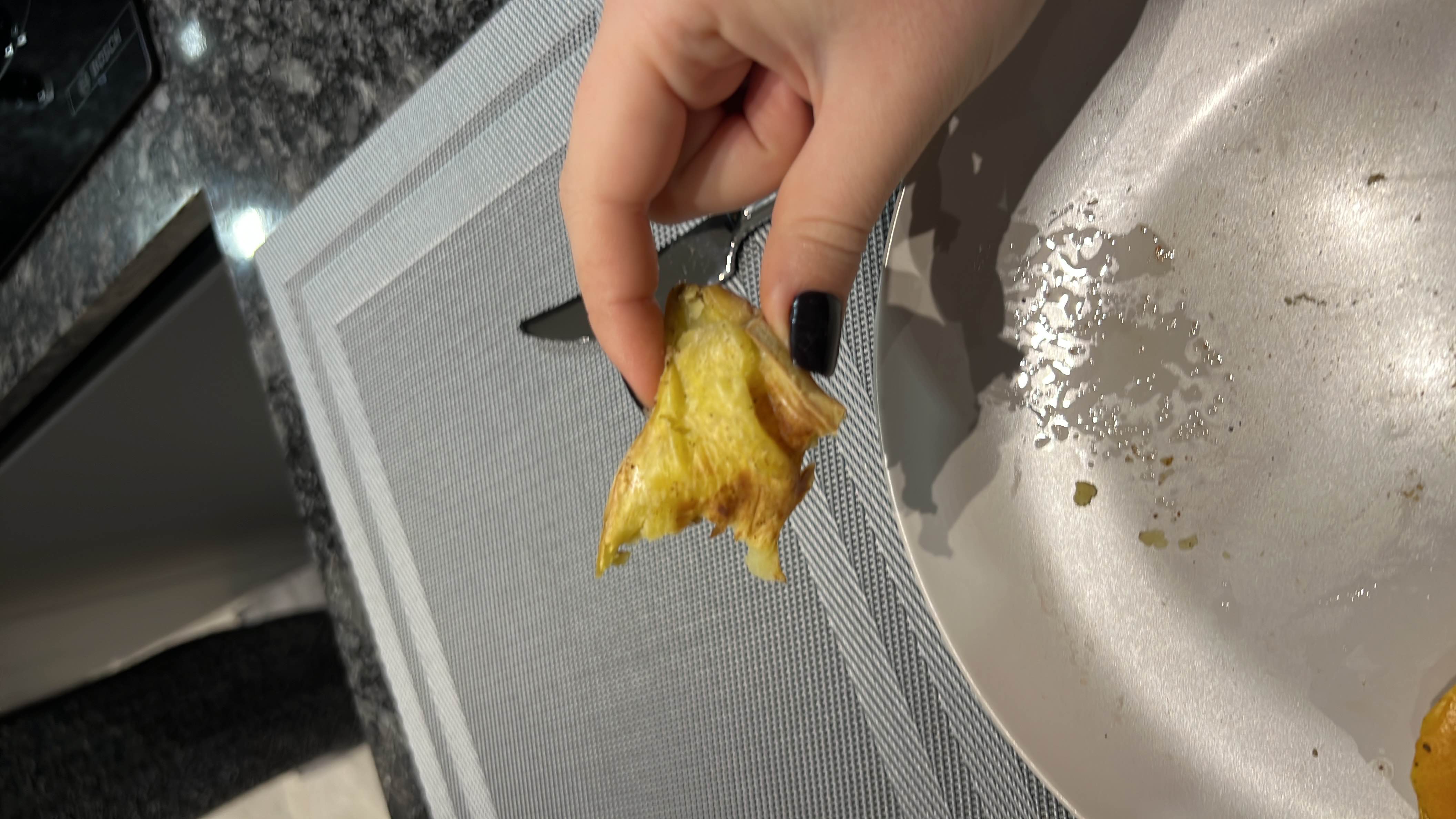 A partially eaten baked potato with a crispy skin and soft interior, likely seasoned with some oil or butter.