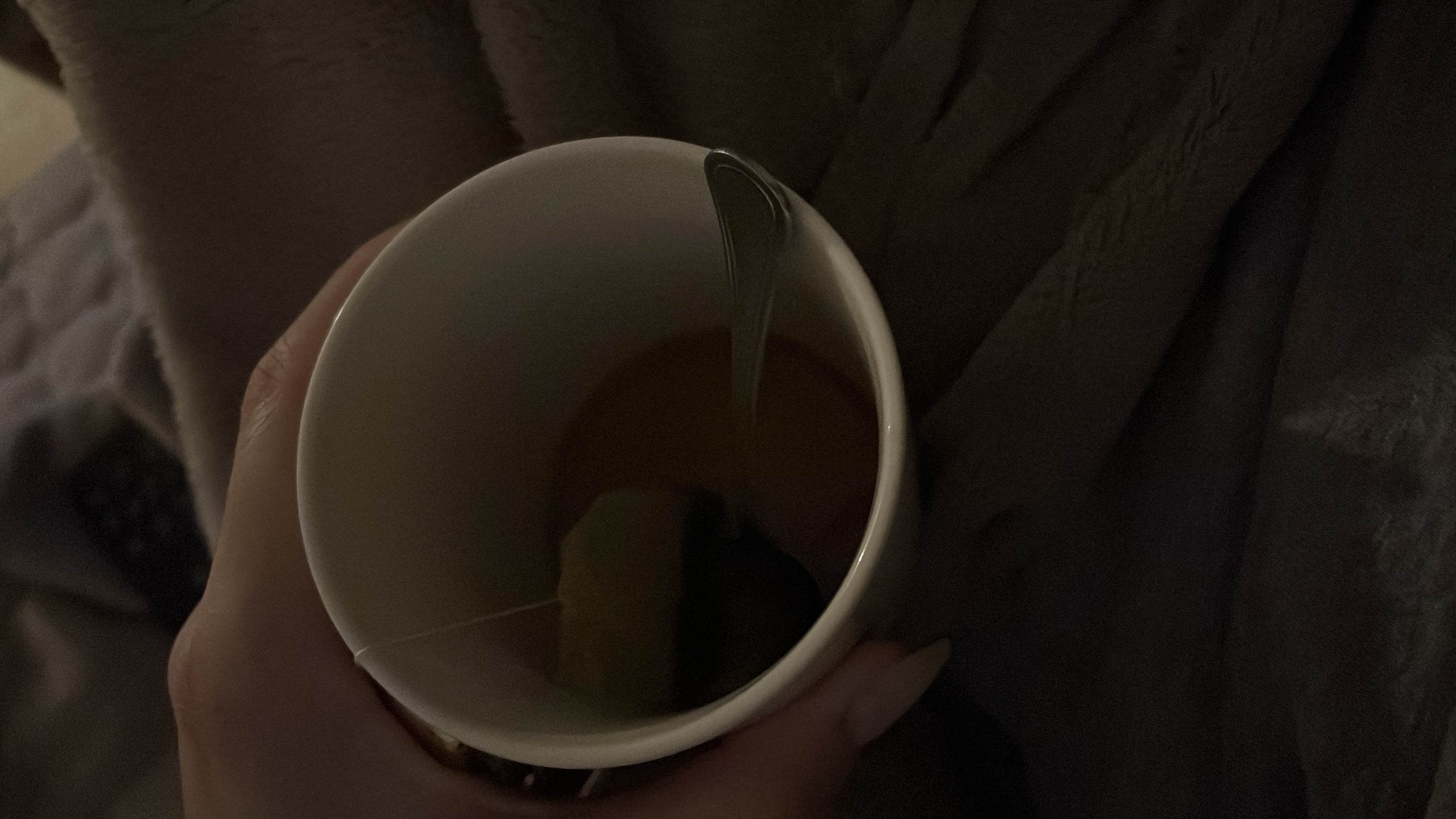 A cup of hot tea with a tea bag and a spoon, providing minimal calories and no significant macronutrients.