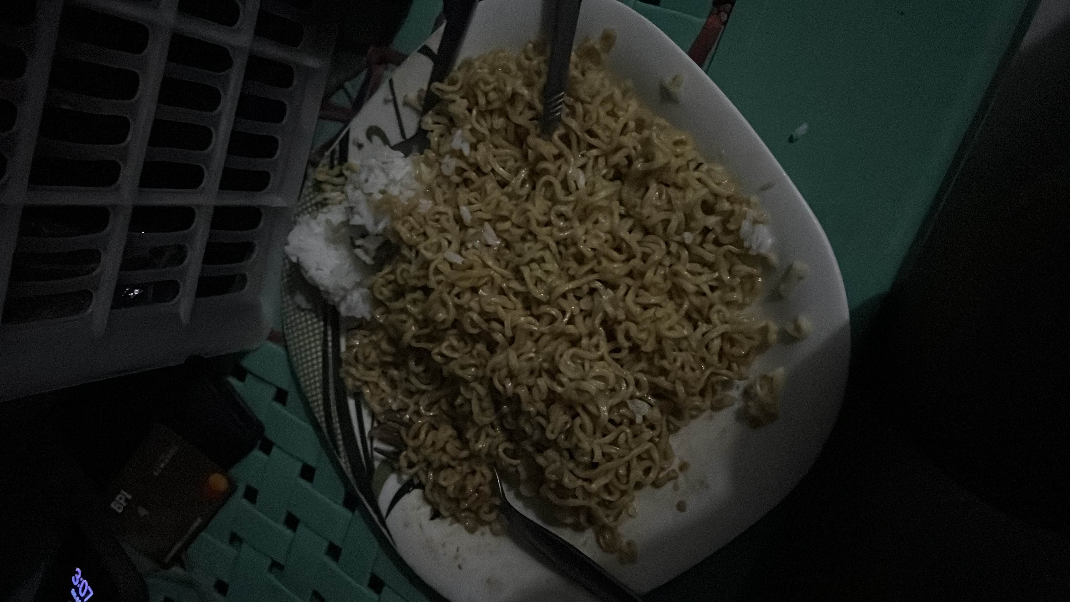 A plate containing instant noodles mixed with white rice, providing a high-carb and moderate-fat meal with minimal protein content.