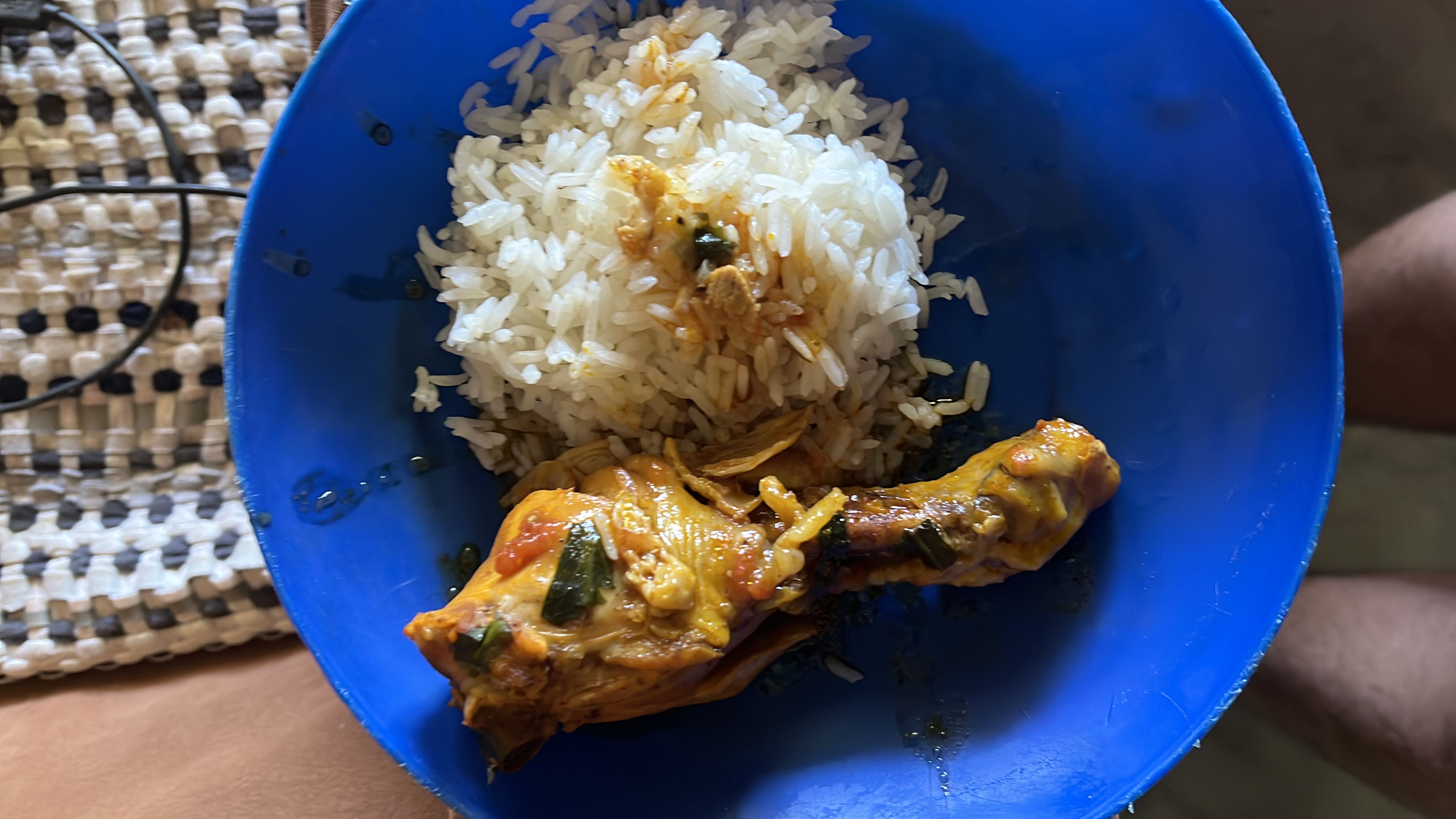 A meal consisting of a cooked chicken drumstick with a tomato-based sauce and a serving of white rice.