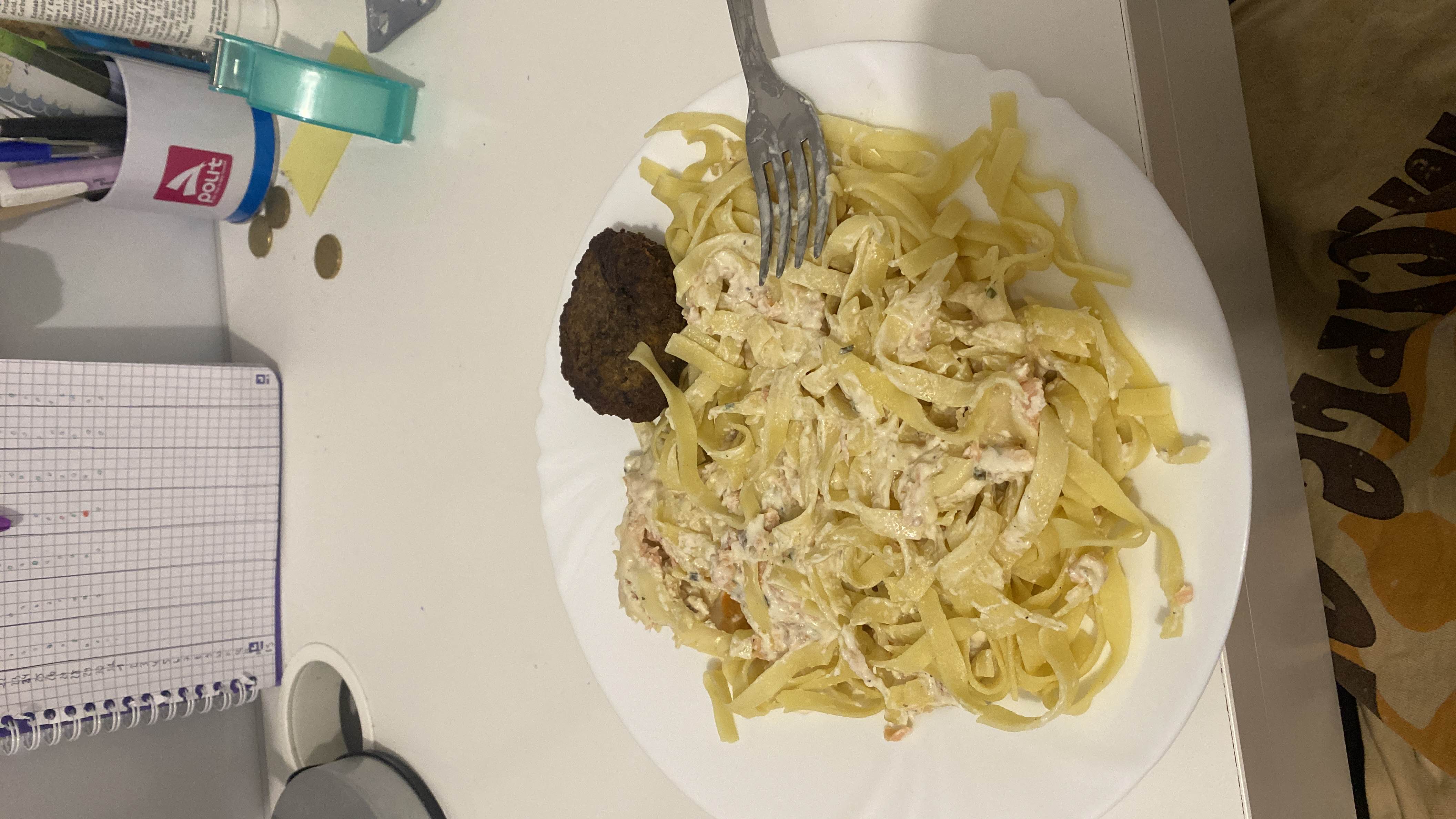 A plate of creamy tagliatelle pasta with chicken and a side of falafel, providing a balanced mix of protein, carbs, and fats.