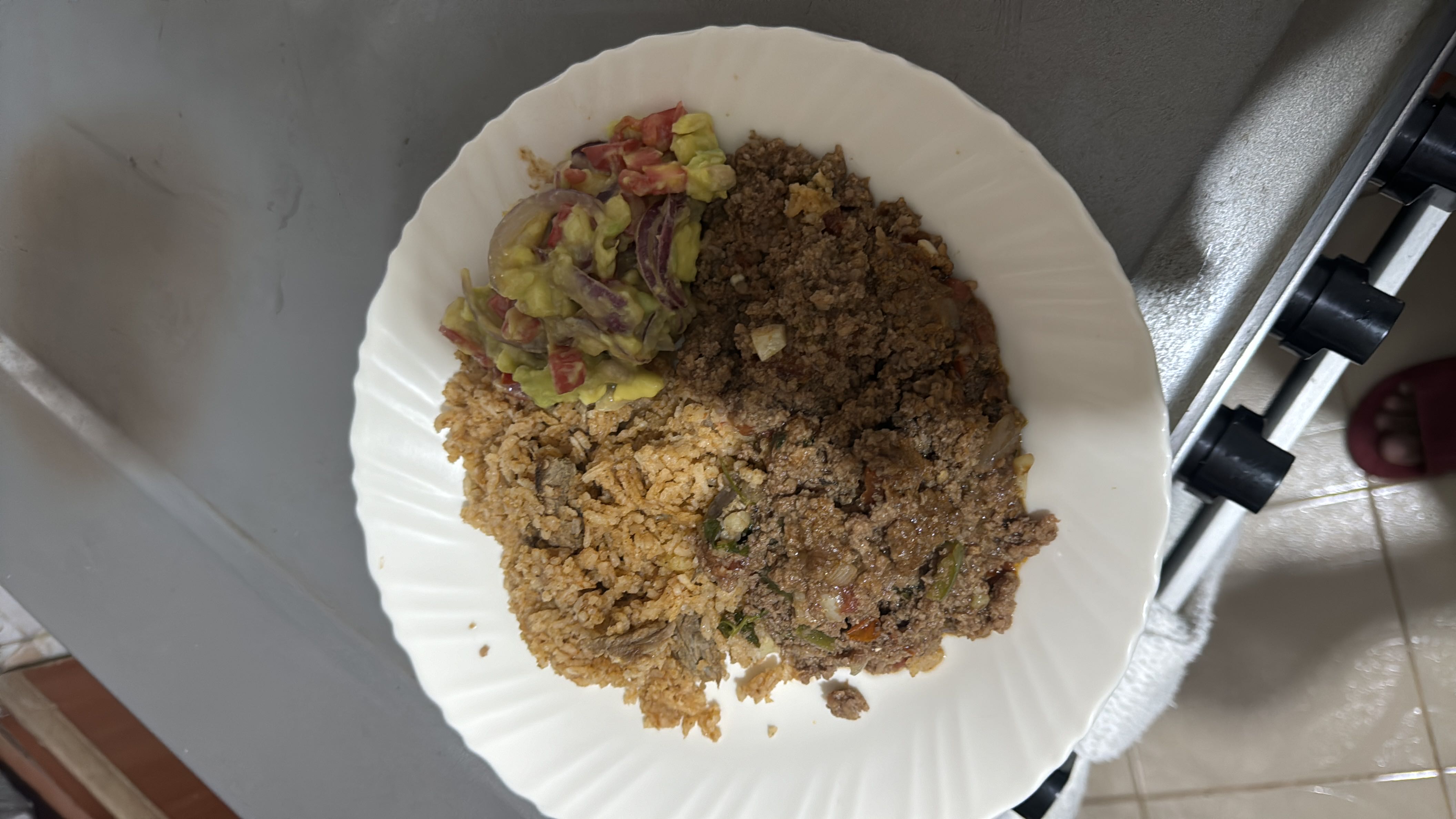 A balanced meal consisting of spiced rice, minced meat, and avocado salad, providing a good mix of protein, carbohydrates, and healthy fats.