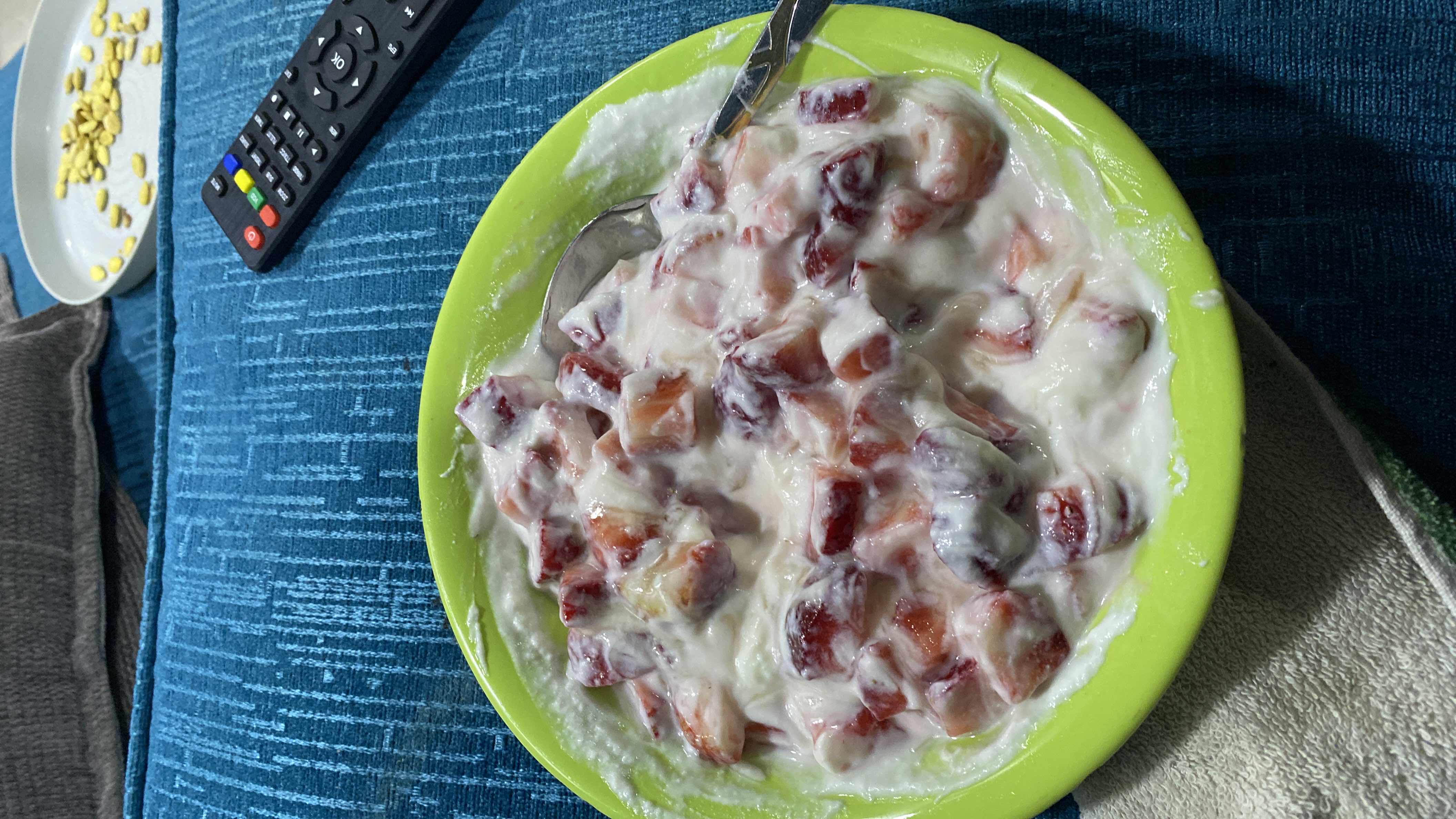 A bowl of yogurt mixed with chopped strawberries and peaches, providing a nutritious and balanced snack.