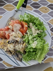 A healthy salad with lettuce, tomatoes, mushrooms, cheese, chicken, and dressing, providing a balanced mix of protein, fats, and carbohydrates.