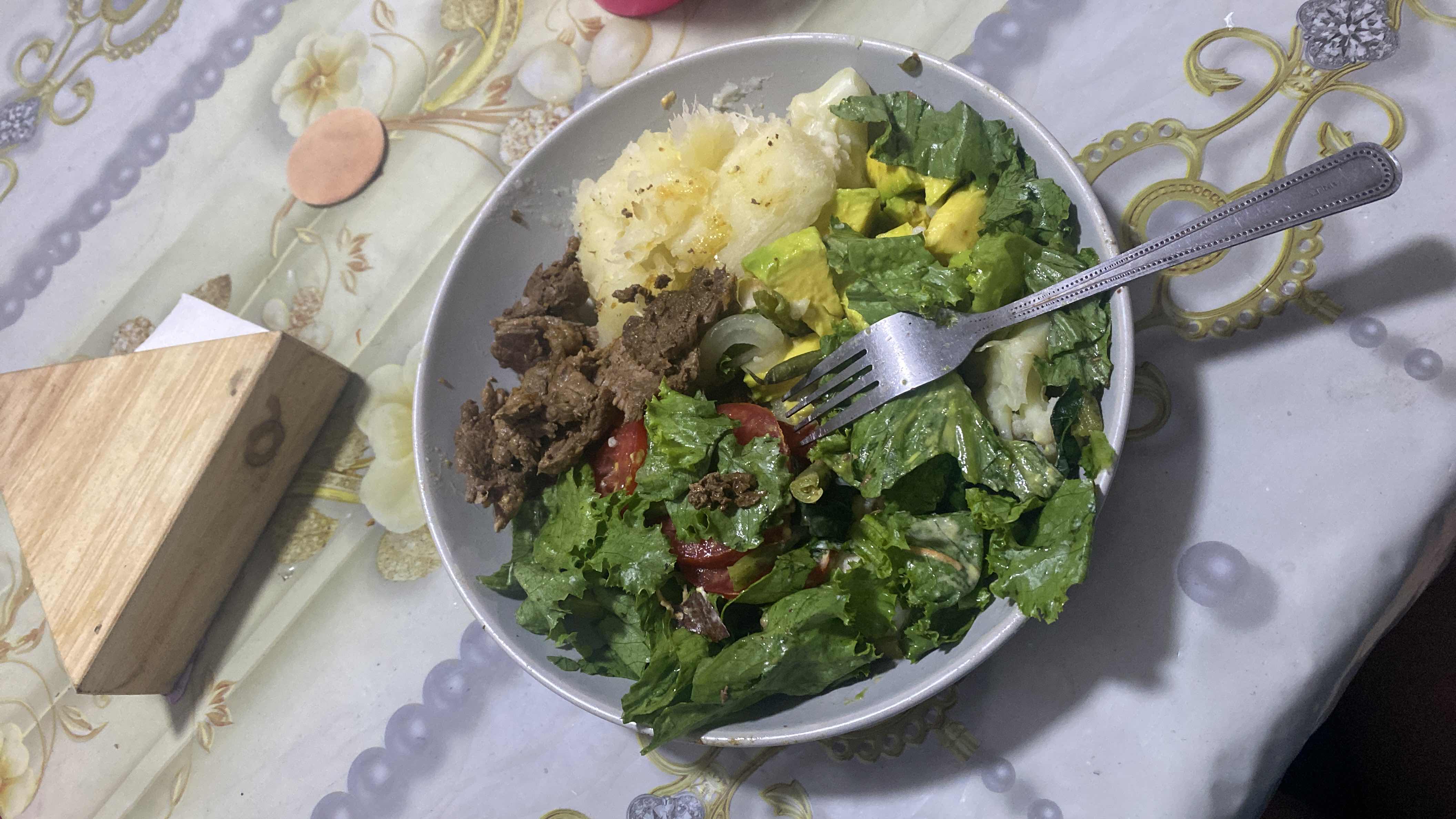 A balanced meal consisting of beef, fresh vegetables, avocado, and cassava, providing a good mix of protein, healthy fats, and carbohydrates.