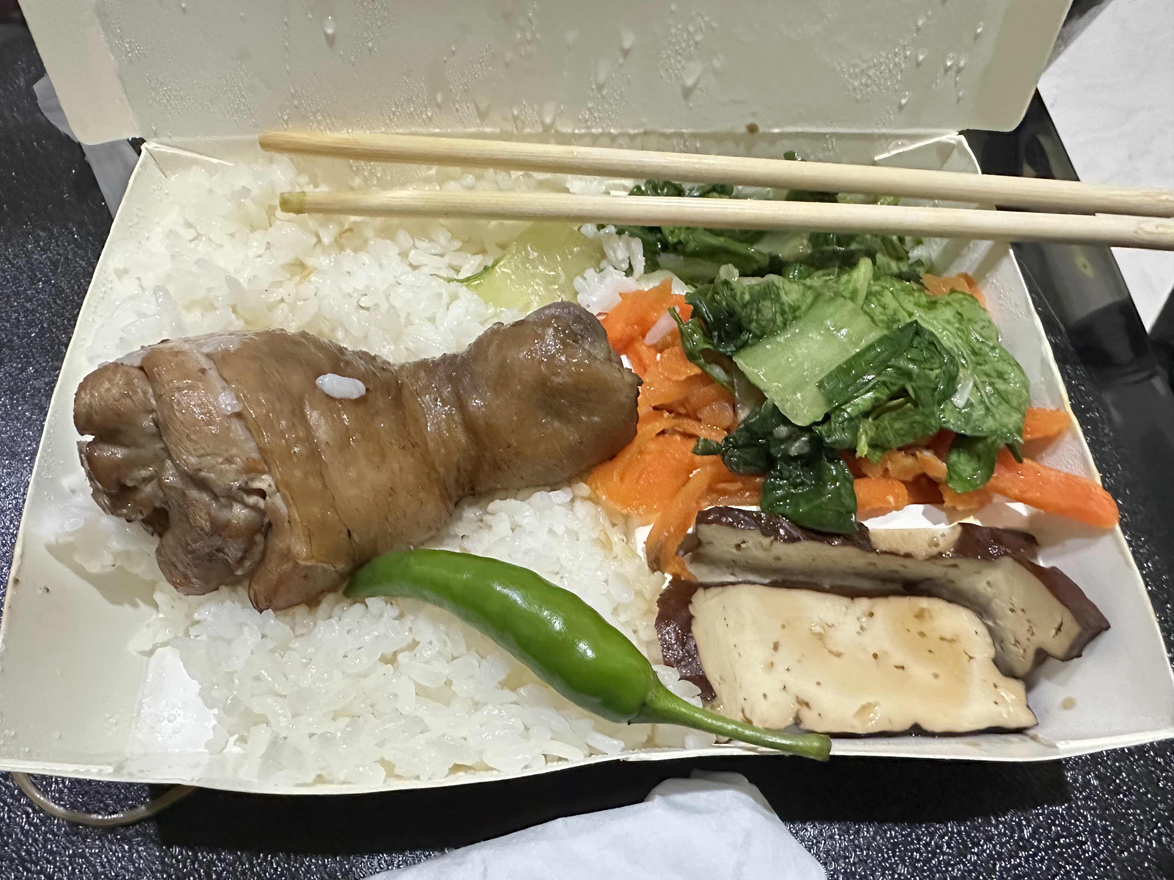 A balanced meal containing a braised chicken leg, white rice, vegetables, and mushrooms, providing a good mix of protein, carbohydrates, and fiber.