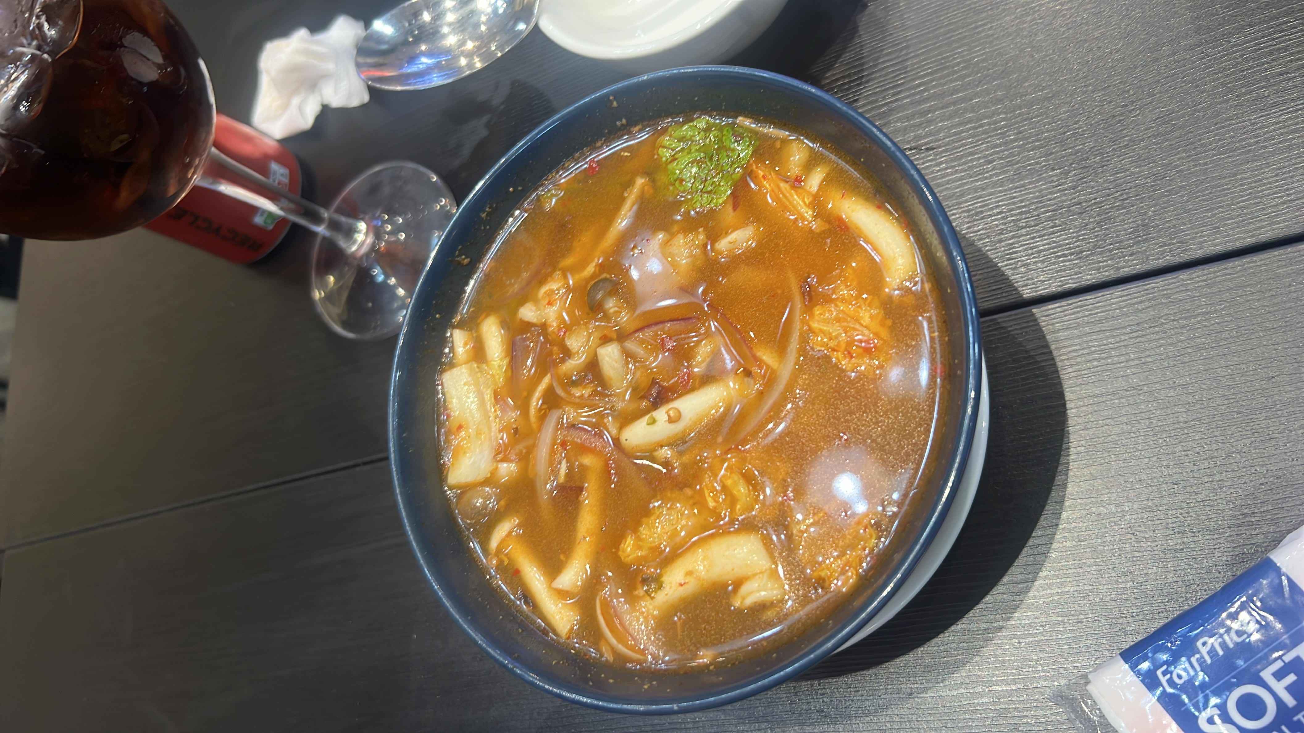 A spicy and sour tom yum soup with chicken, mushrooms, and aromatic herbs, offering a balanced mix of protein, carbs, and fats.