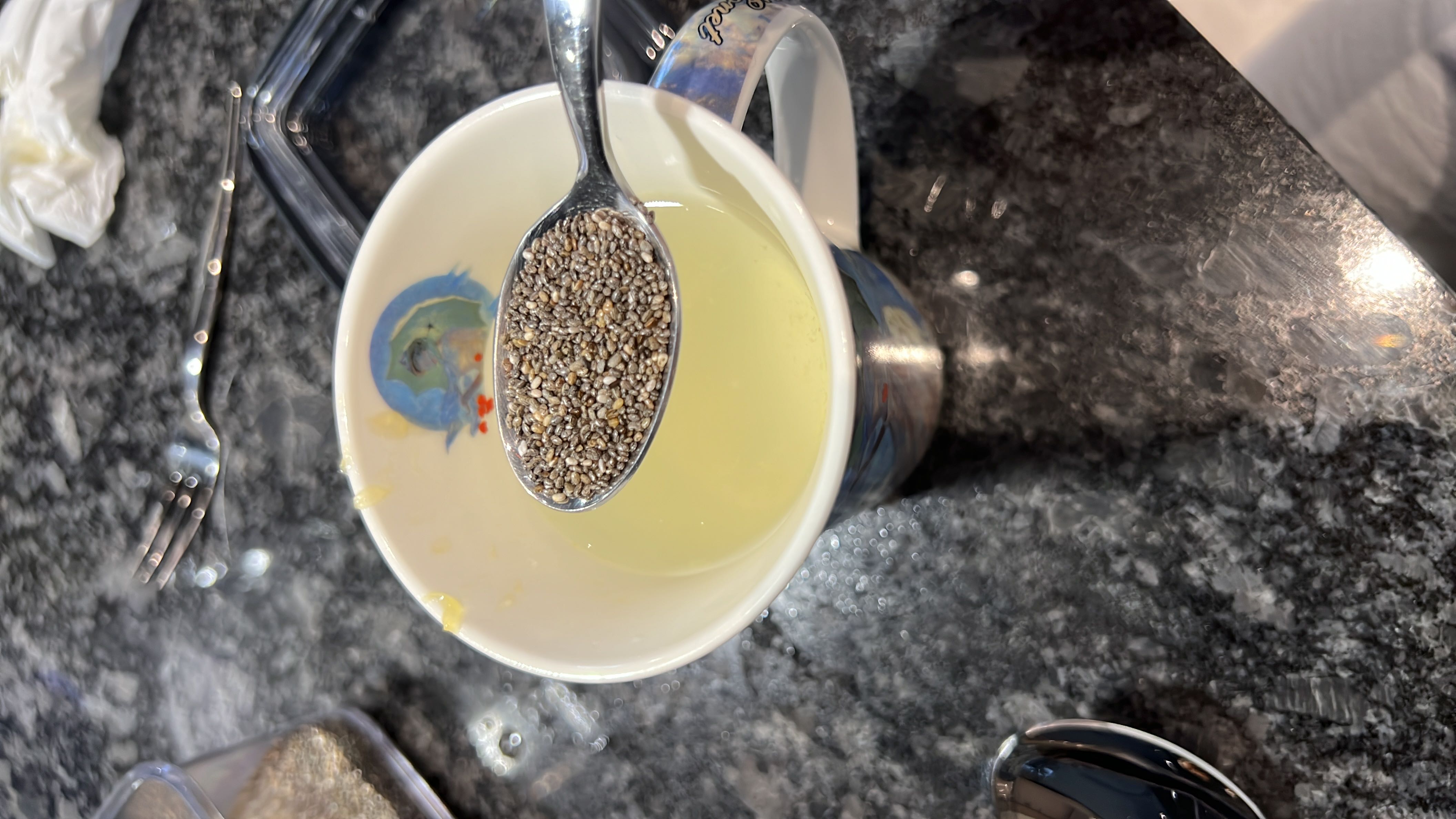 A cup containing a liquid with a spoonful of chia seeds, which are rich in fiber, protein, and healthy fats.