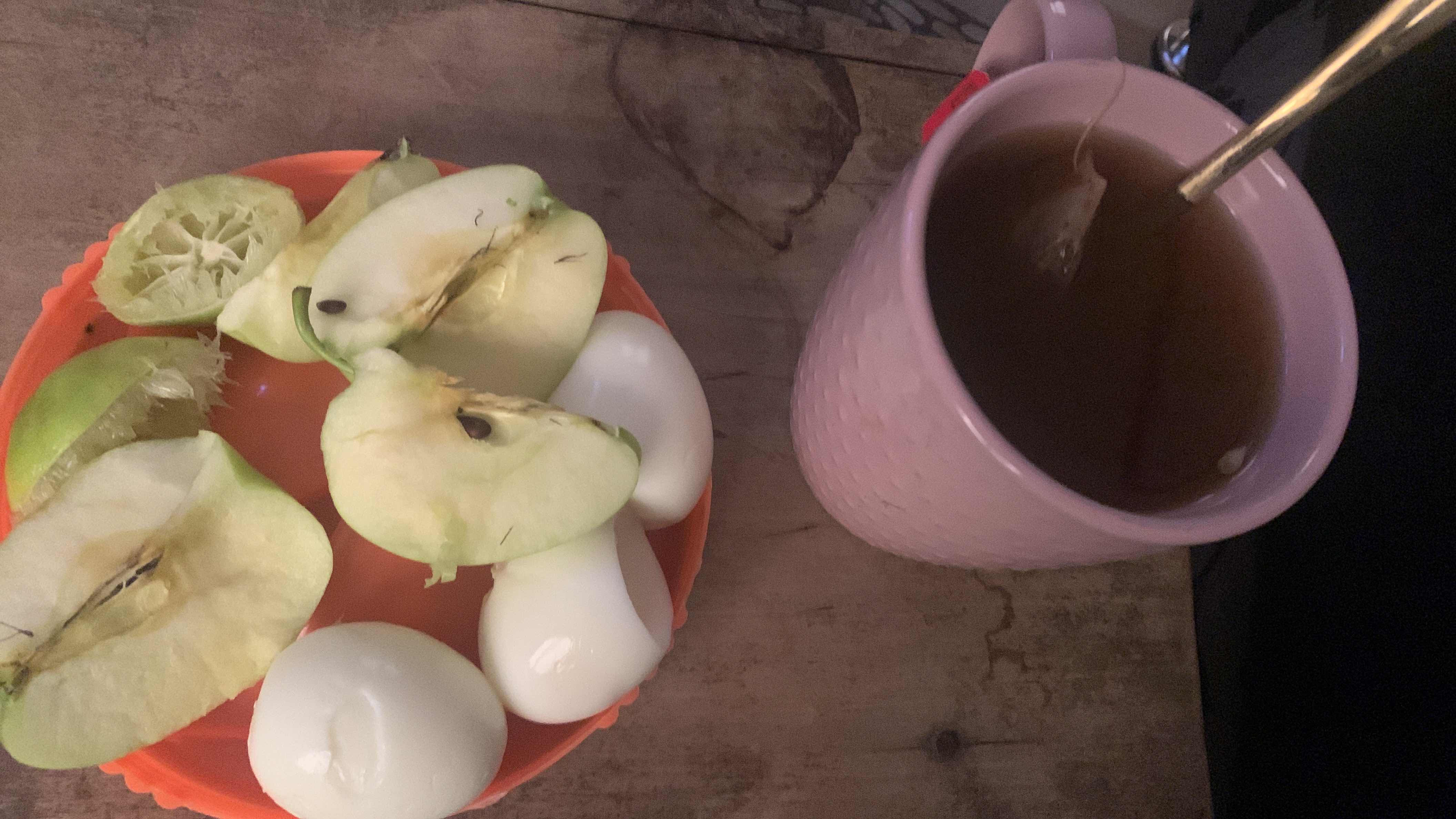A healthy meal consisting of boiled eggs, green apple, lemon, and tea, providing a balanced mix of protein, carbs, and fats.