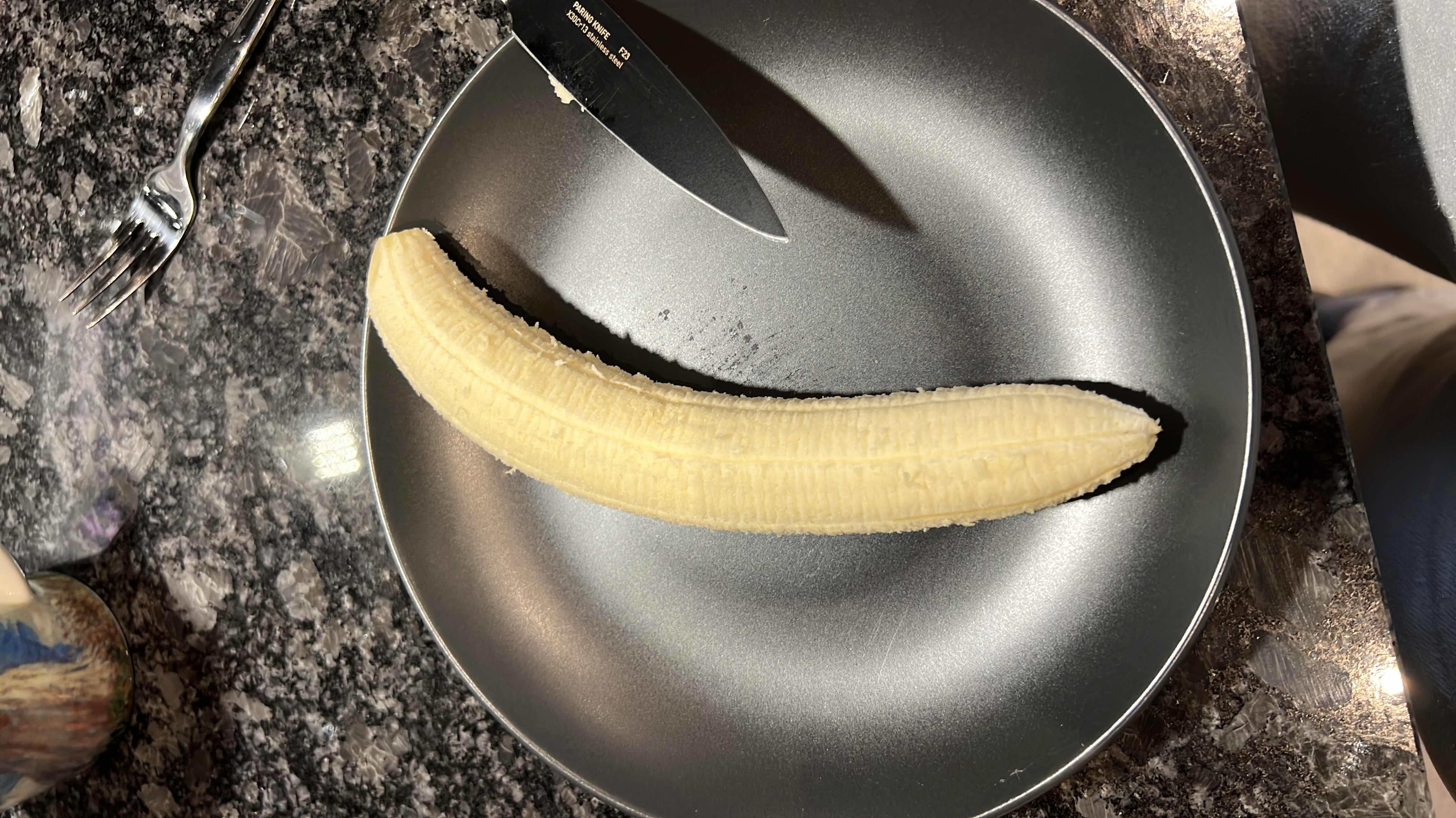 A peeled banana on a black plate, providing a nutritious source of carbohydrates and essential vitamins.