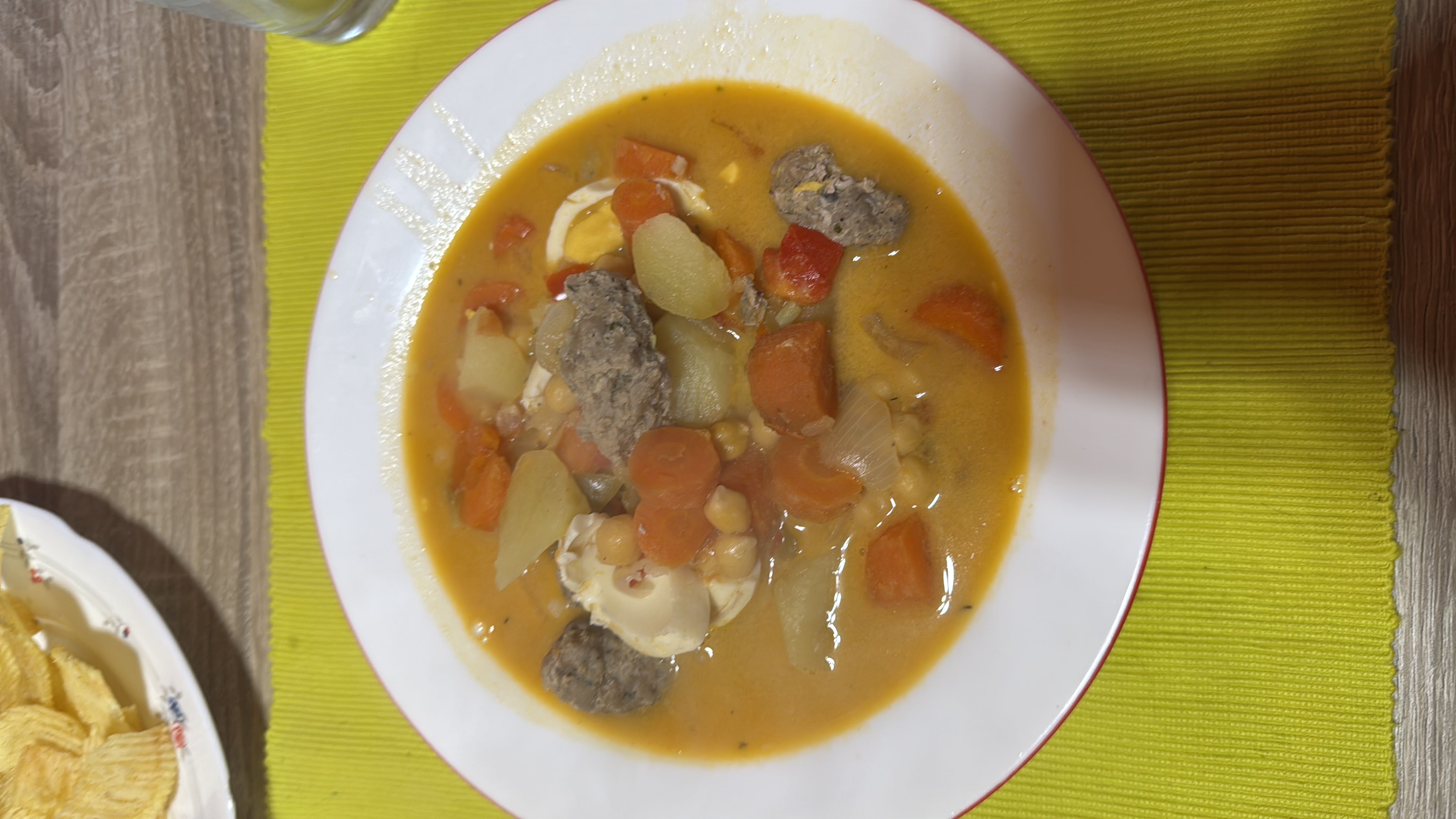 A hearty soup containing vegetables, chickpeas, ground meat, and boiled egg, providing a balanced mix of protein, carbs, and fats.