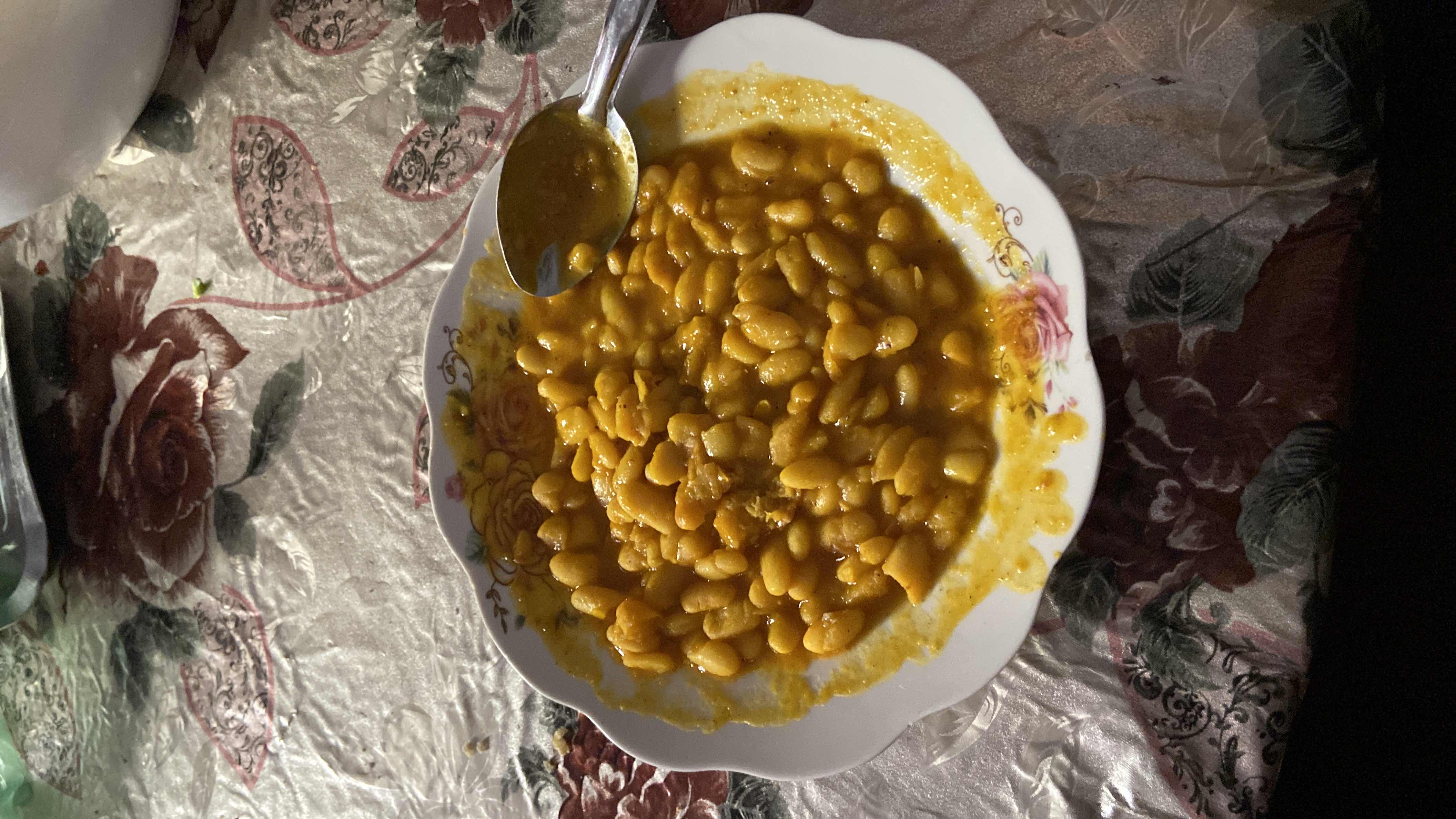 A plate of cooked white beans in a tomato-based sauce, likely seasoned with spices and olive oil, providing a nutritious and protein-rich meal.