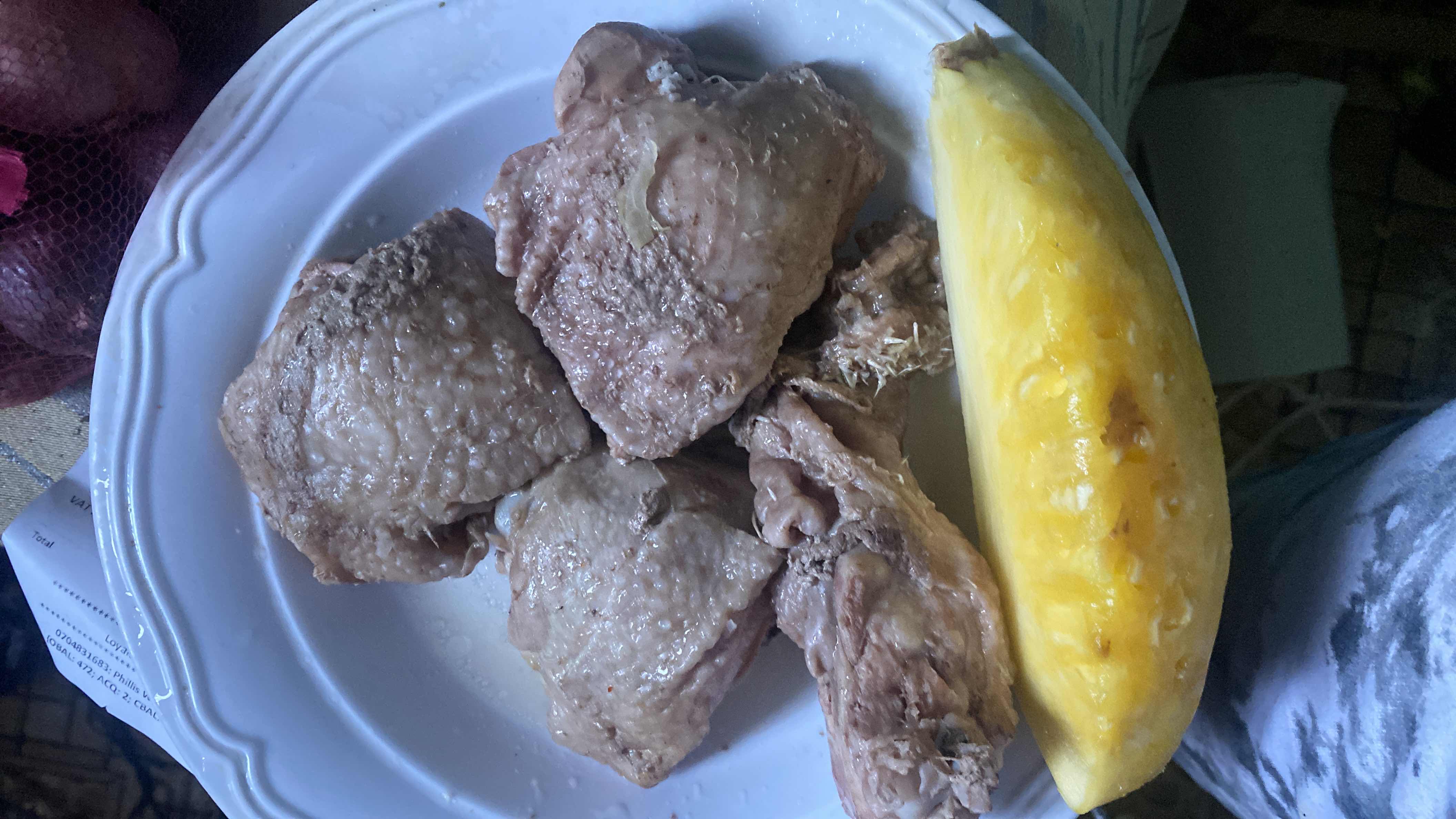 A plate containing boiled chicken pieces and a slice of pineapple, providing a balanced mix of protein and carbohydrates.