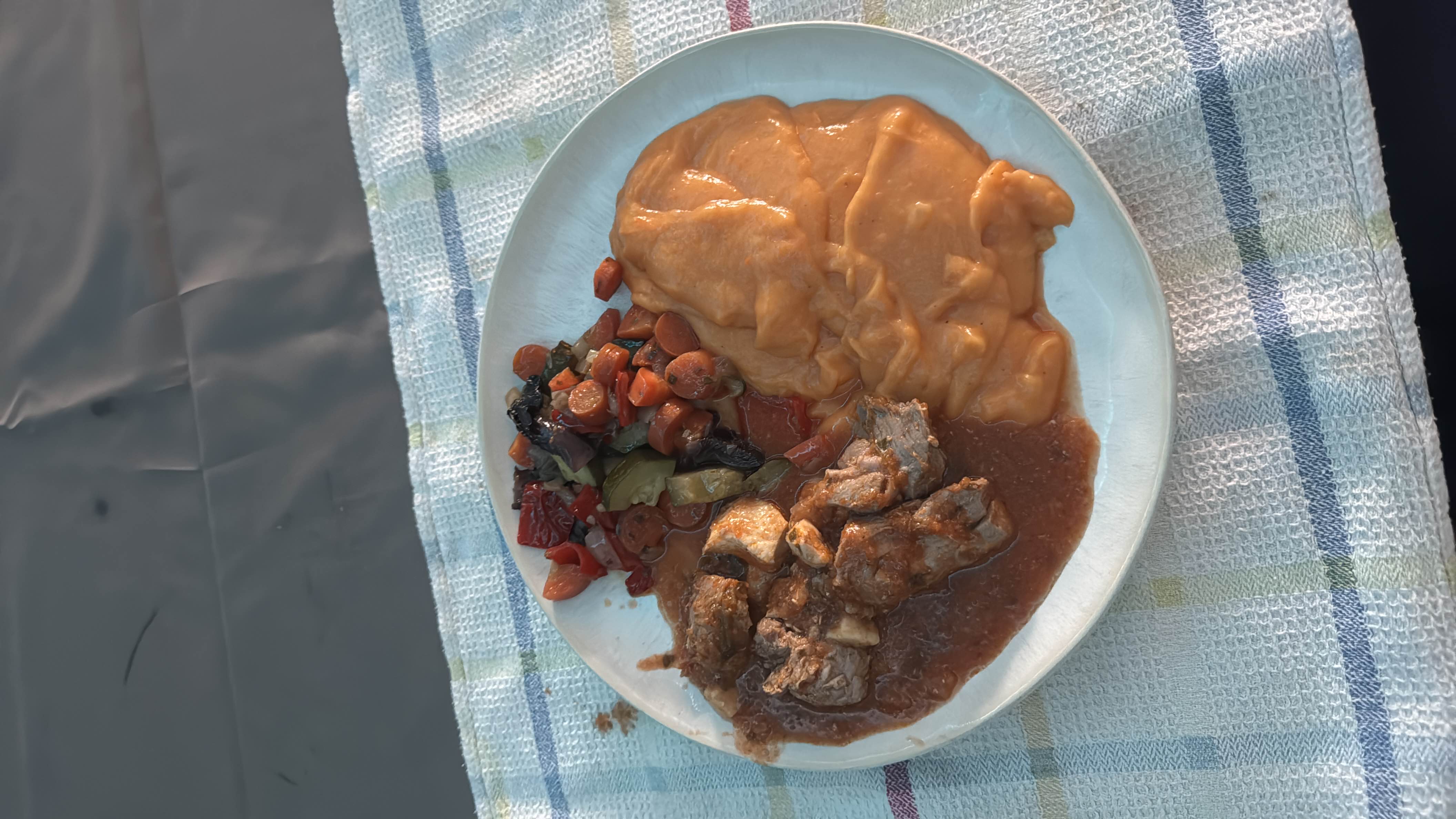 A balanced meal consisting of beef stew in a rich sauce, mashed sweet potatoes, and sautéed vegetables, providing a good mix of protein, carbohydrates, and essential nutrients.