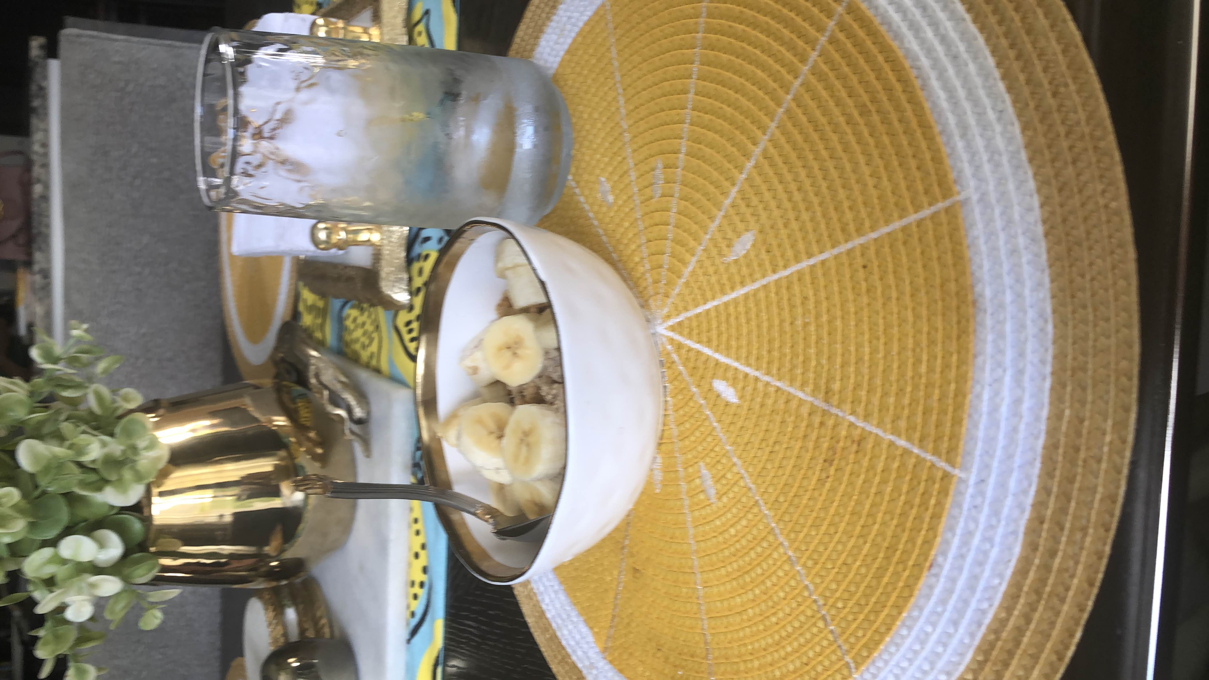 A nutritious bowl of granola and corn flakes topped with banana slices, served with Leche descremada light, providing a balanced mix of carbohydrates, protein, and healthy fats.