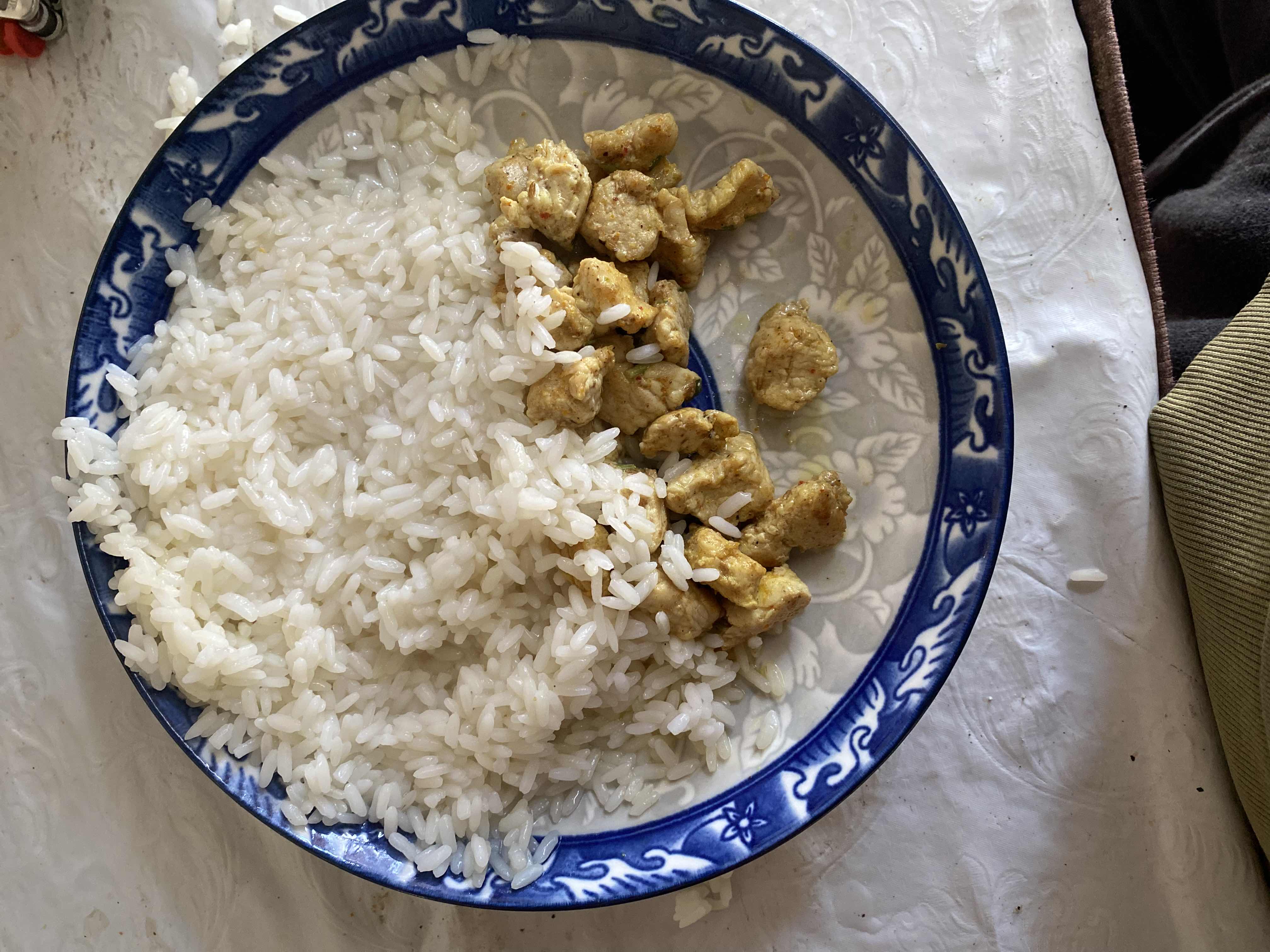 A plate containing white rice and seasoned chicken, providing a balanced mix of carbohydrates and protein with moderate fat content.