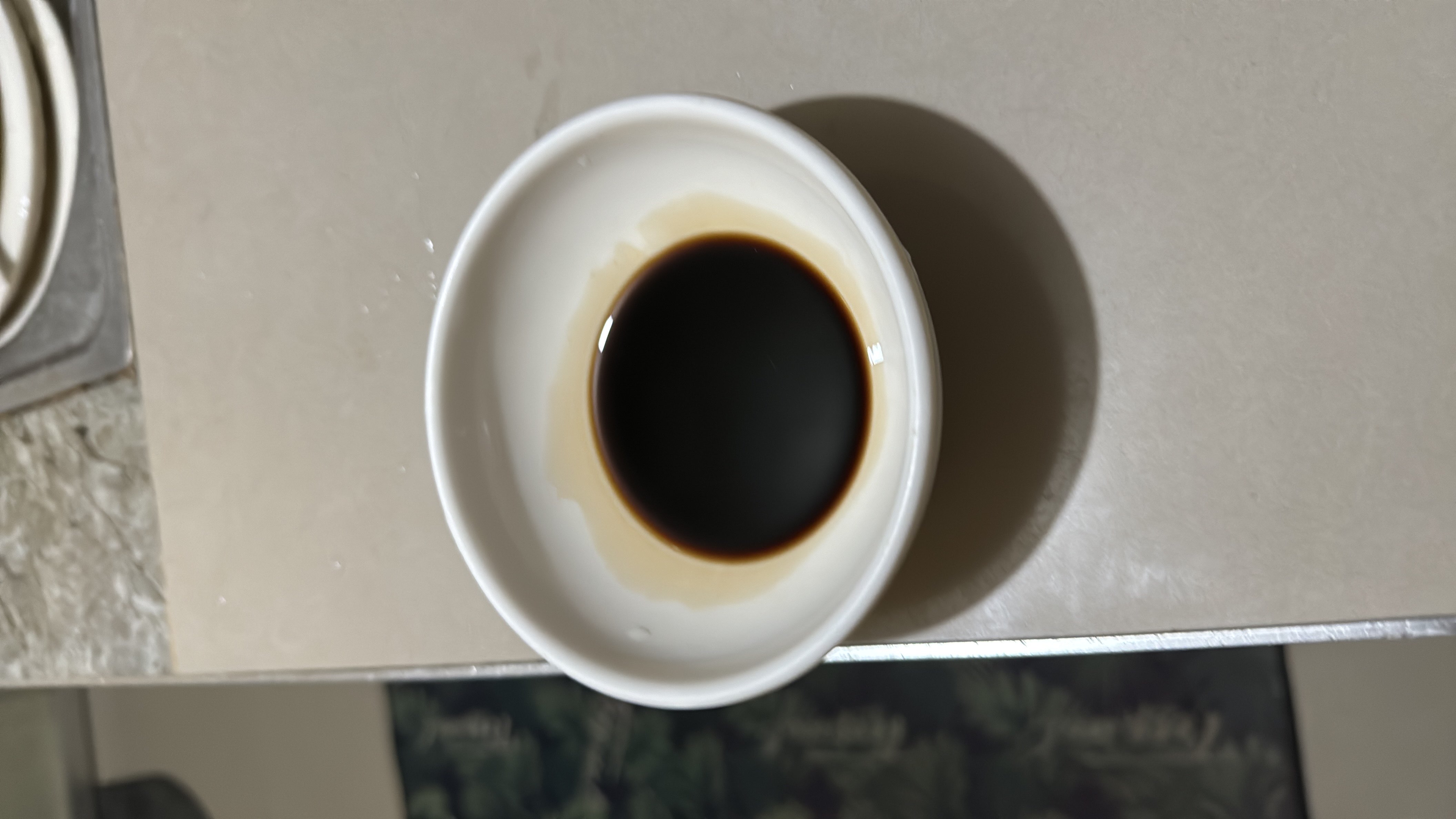 A small dish containing soy sauce, a low-calorie condiment rich in umami flavor, commonly used in Asian cuisine.