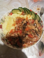 A balanced meal consisting of chicken with onions, mushrooms, bell peppers, and carrots in sauce, served with mashed potatoes and fresh cucumber slices.