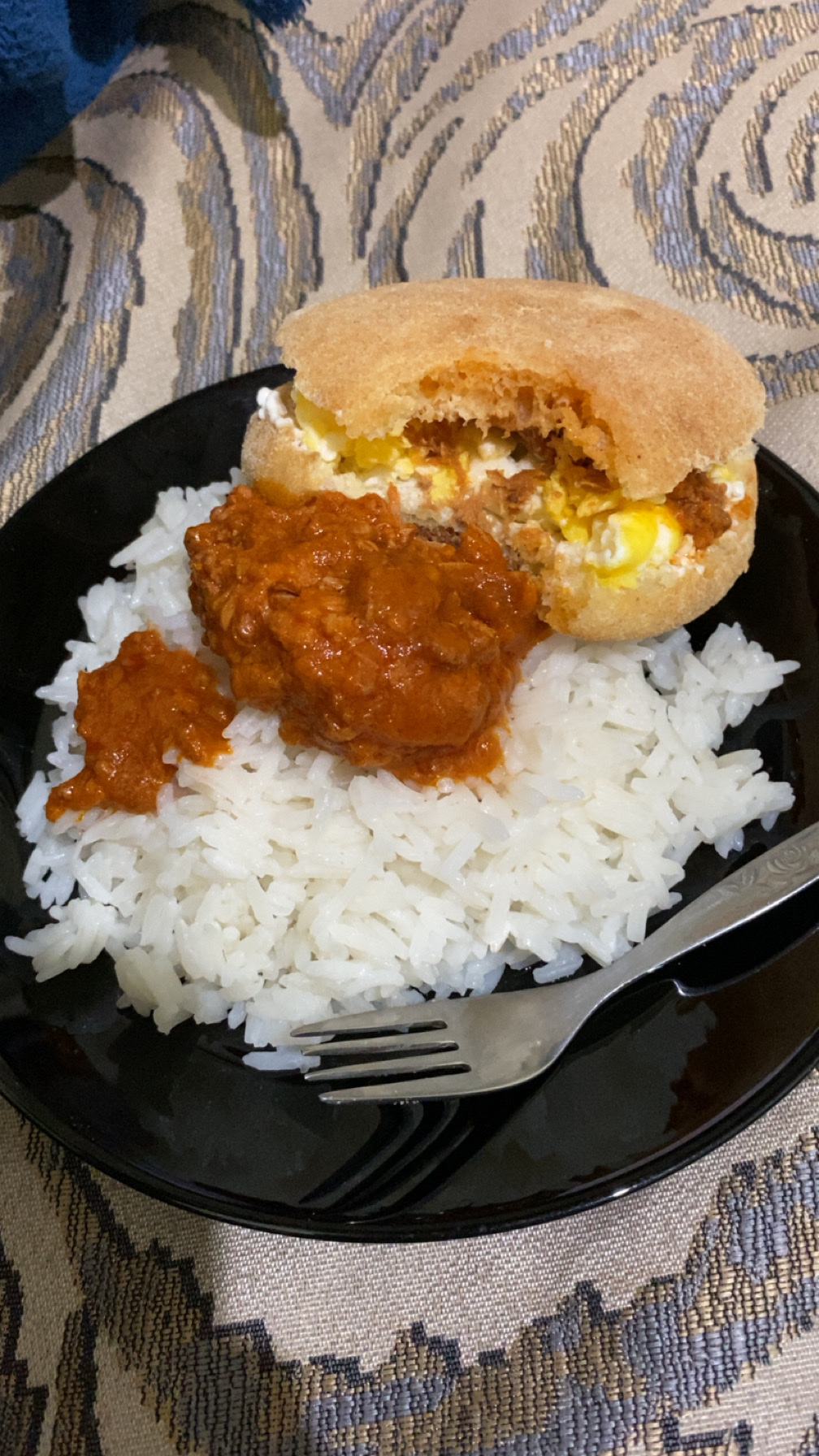 A meal consisting of white rice with tomato-based meat sauce and an egg sandwich, providing a balanced mix of carbohydrates, protein, and fats.