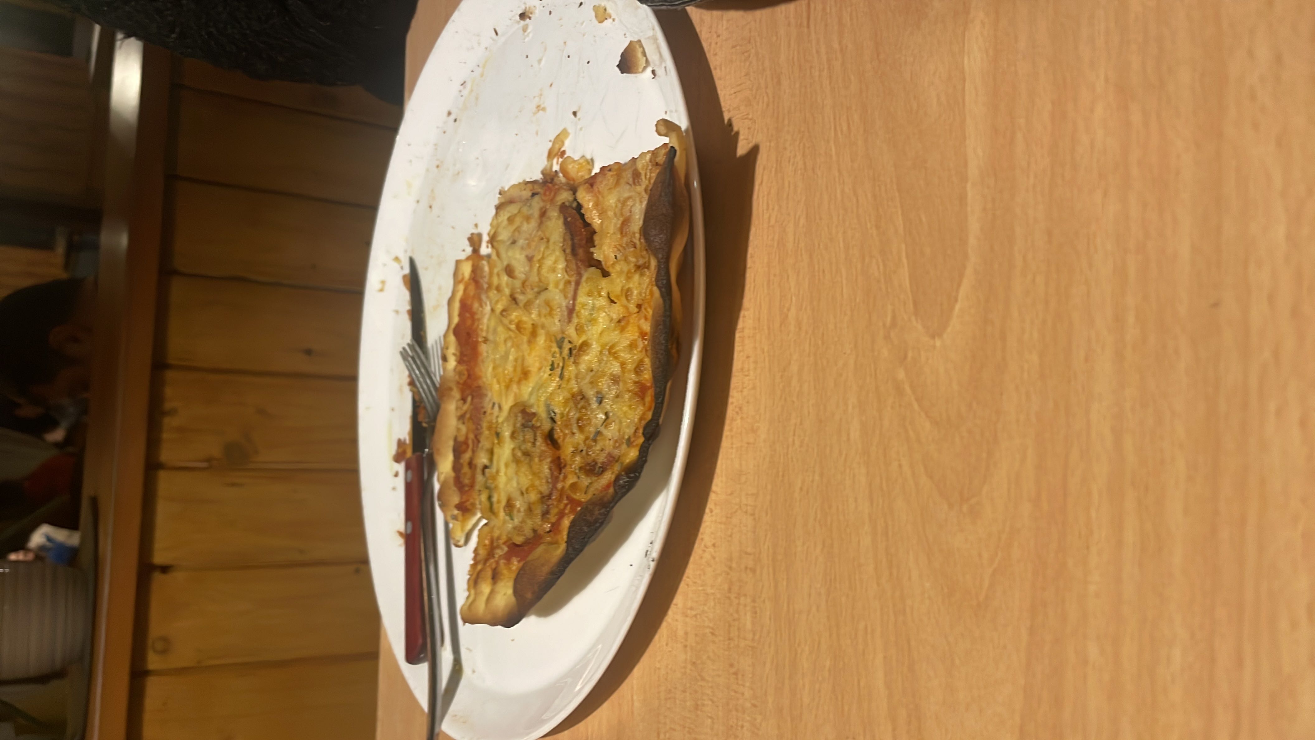 A partially eaten thin-crust pizza with cheese, tomato sauce, and pepperoni, served on a white plate.
