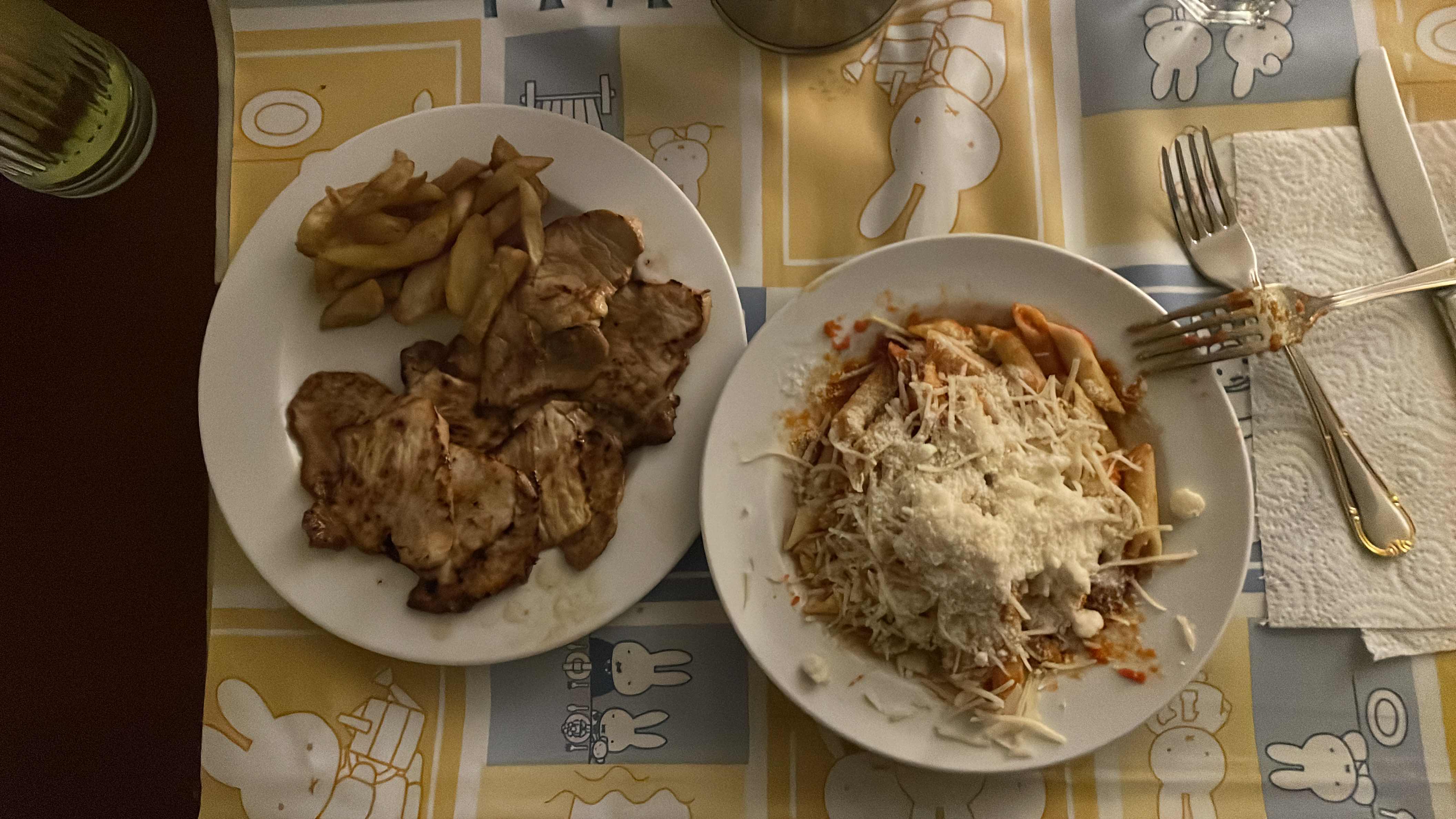 A meal consisting of grilled pork, French fries, and pasta with tomato sauce and cheese, providing a balanced mix of protein, carbohydrates, and fats.