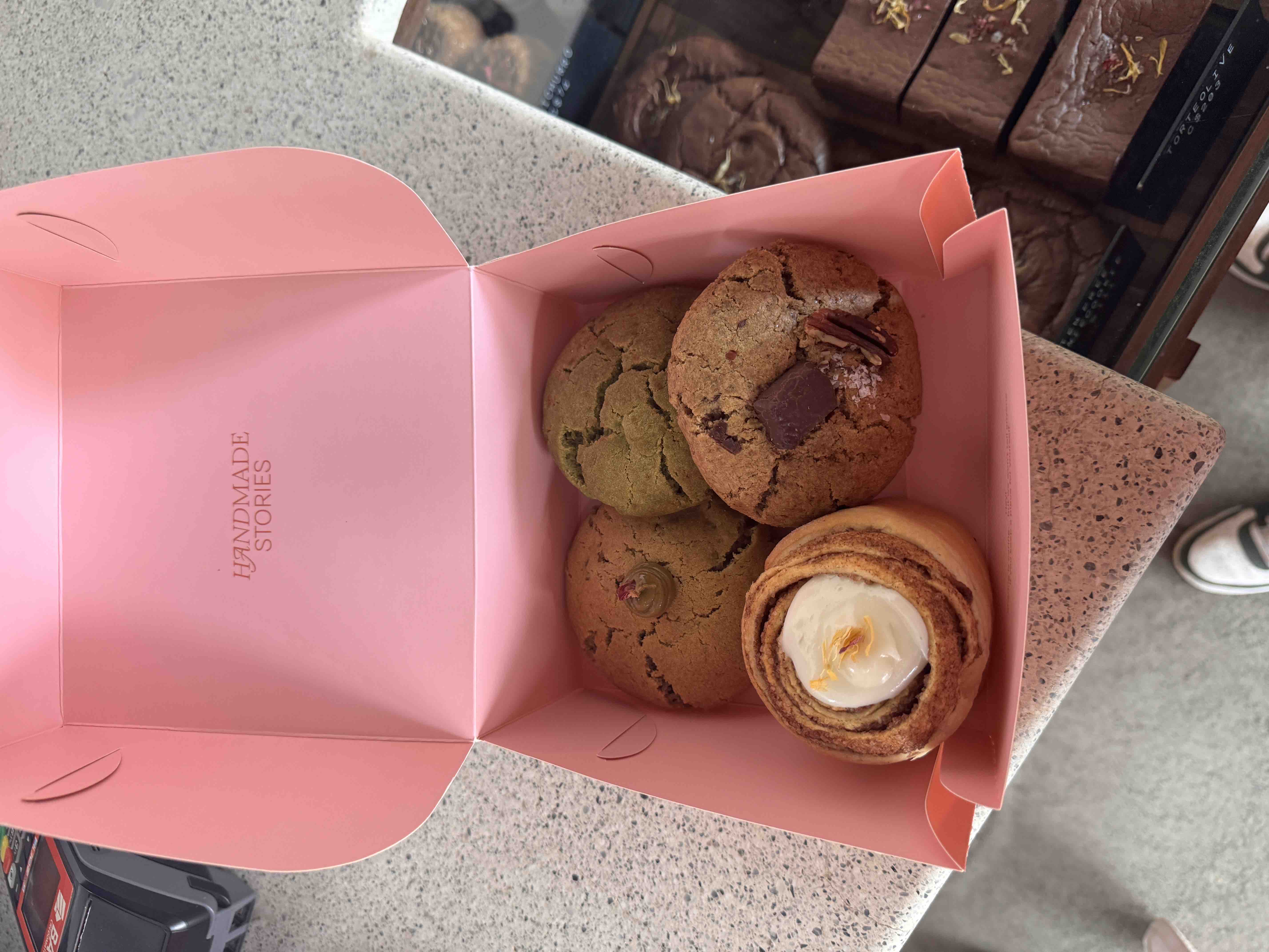 A box of assorted handmade cookies and a cinnamon roll, rich in carbohydrates and fats, with moderate protein content.