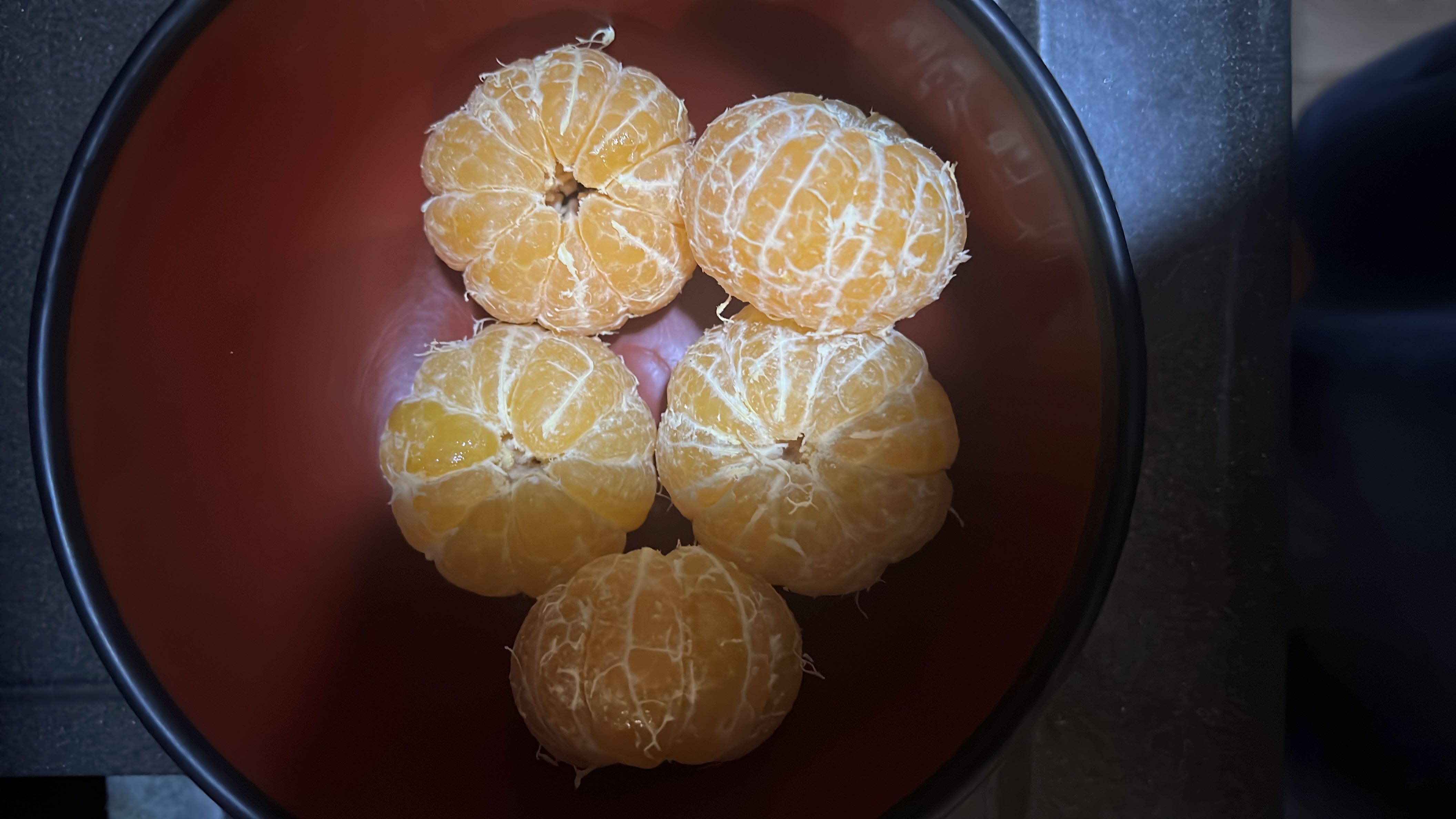 A bowl containing five peeled mandarin oranges, which are rich in vitamin C, fiber, and natural sugars, making them a healthy and refreshing snack.