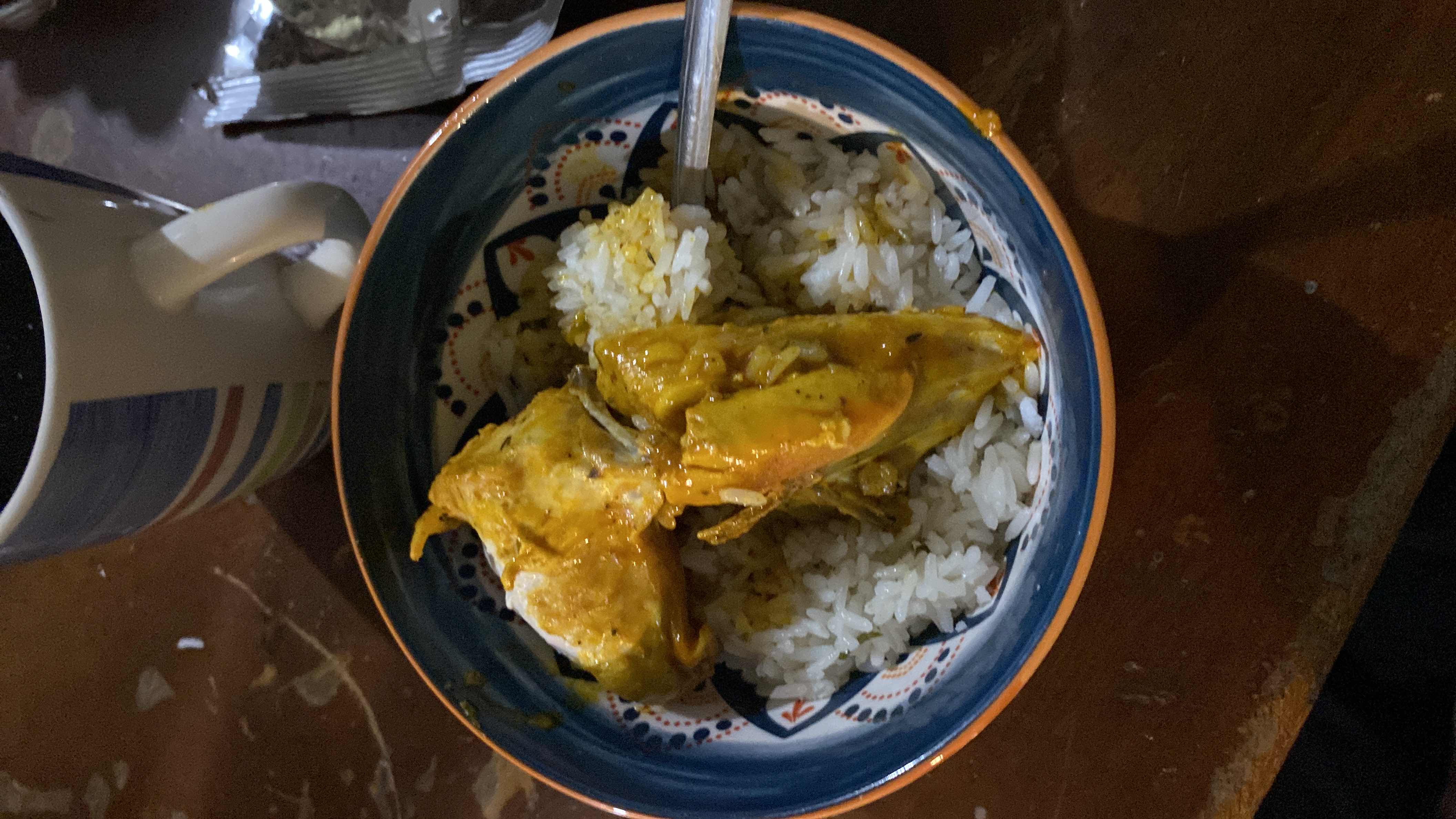 A bowl of white rice served with chicken in a curry sauce, providing a balanced mix of protein, carbohydrates, and fats.