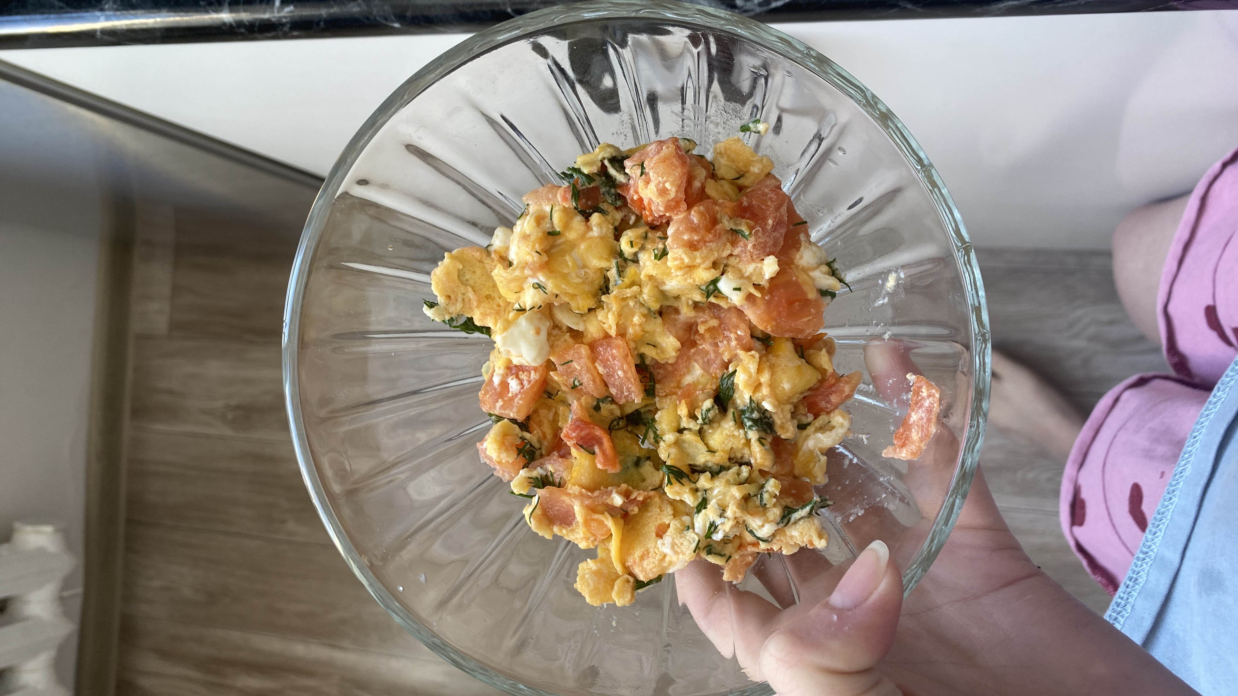 A nutritious scrambled egg dish with tomatoes, cheese, and herbs, providing a balanced mix of protein, fats, and carbohydrates.