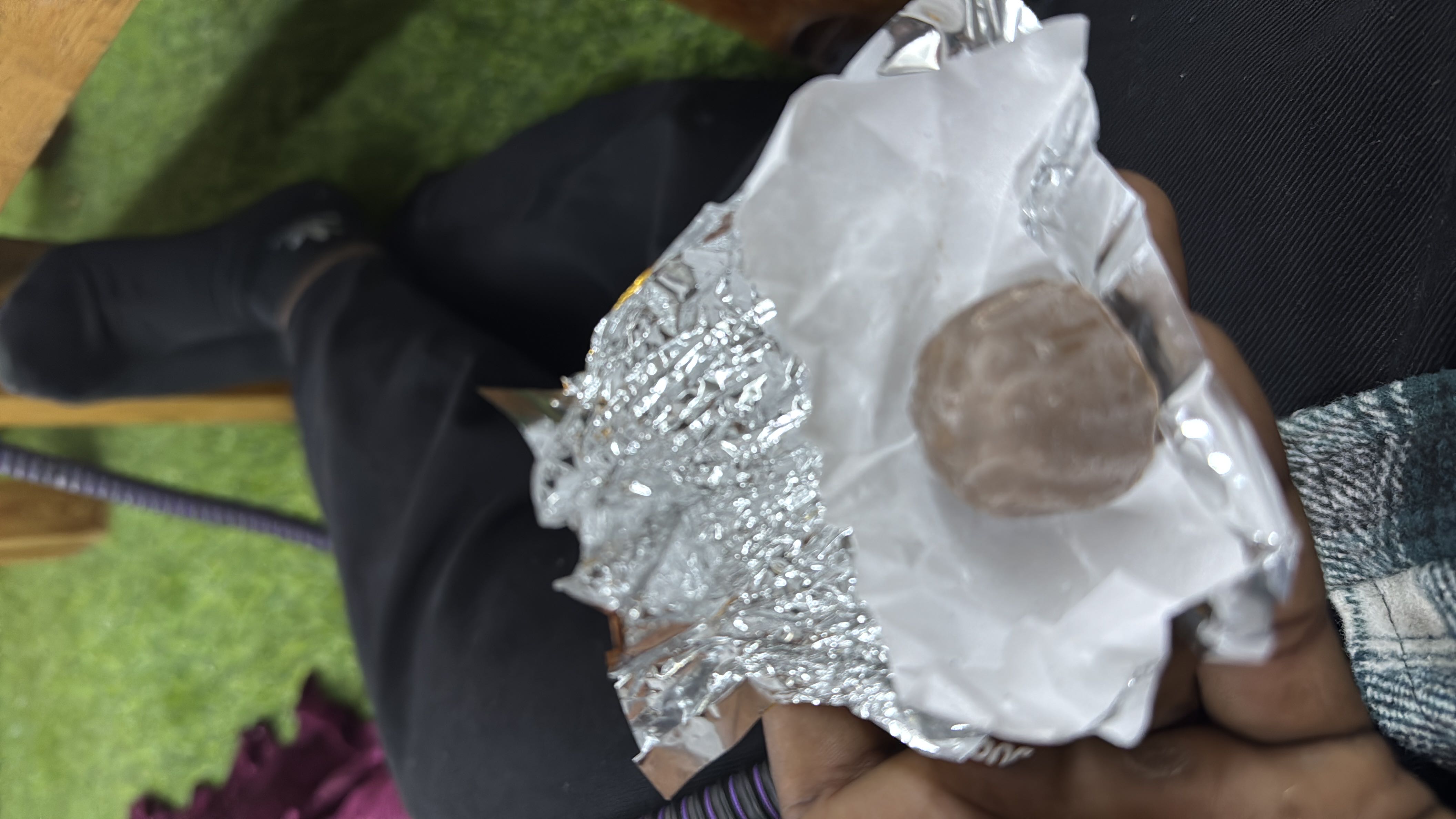 A single milk chocolate truffle with a creamy filling, wrapped in foil.