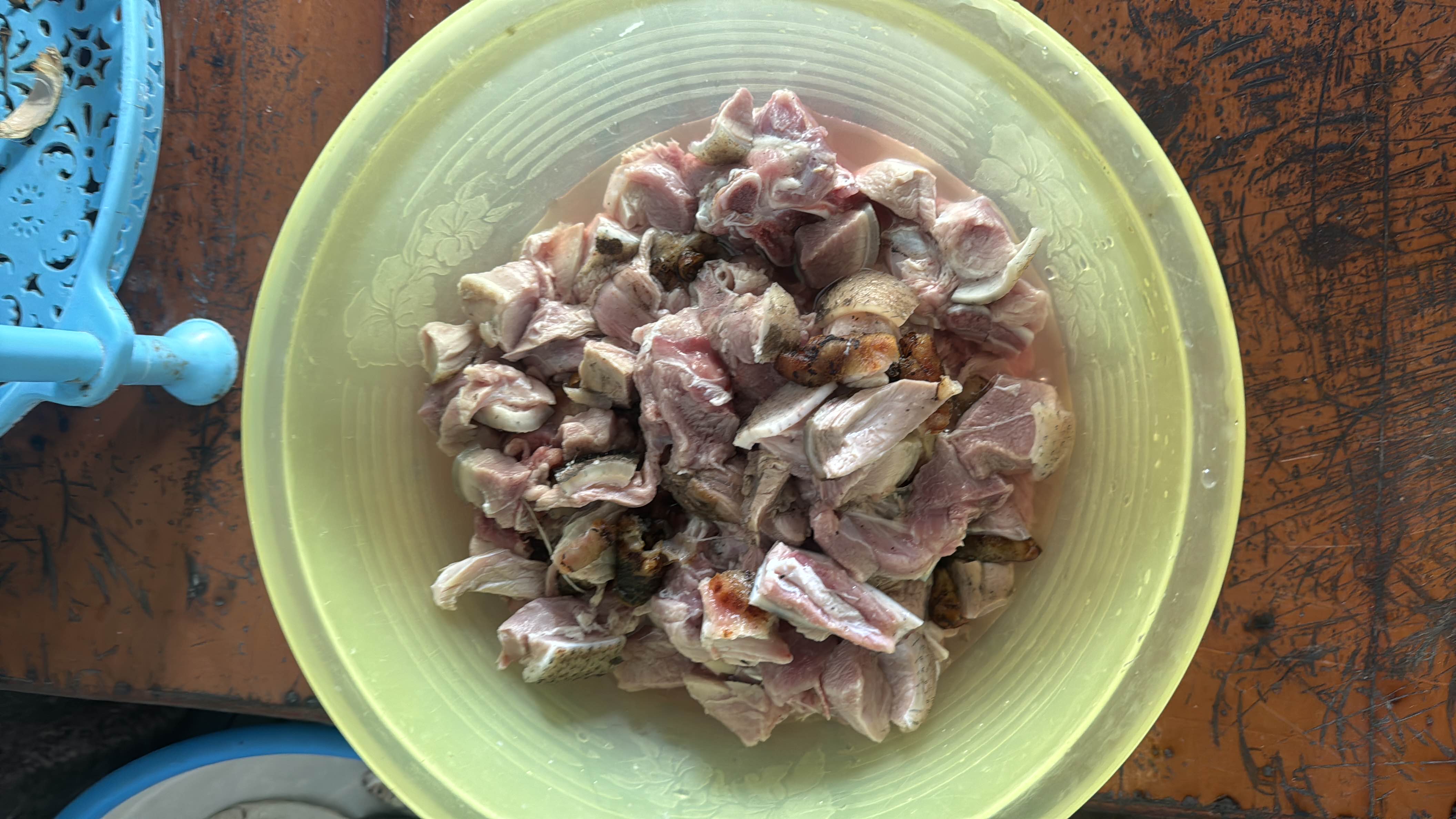 A bowl of freshly chopped raw goat meat, rich in protein and fats, commonly used in various traditional dishes.