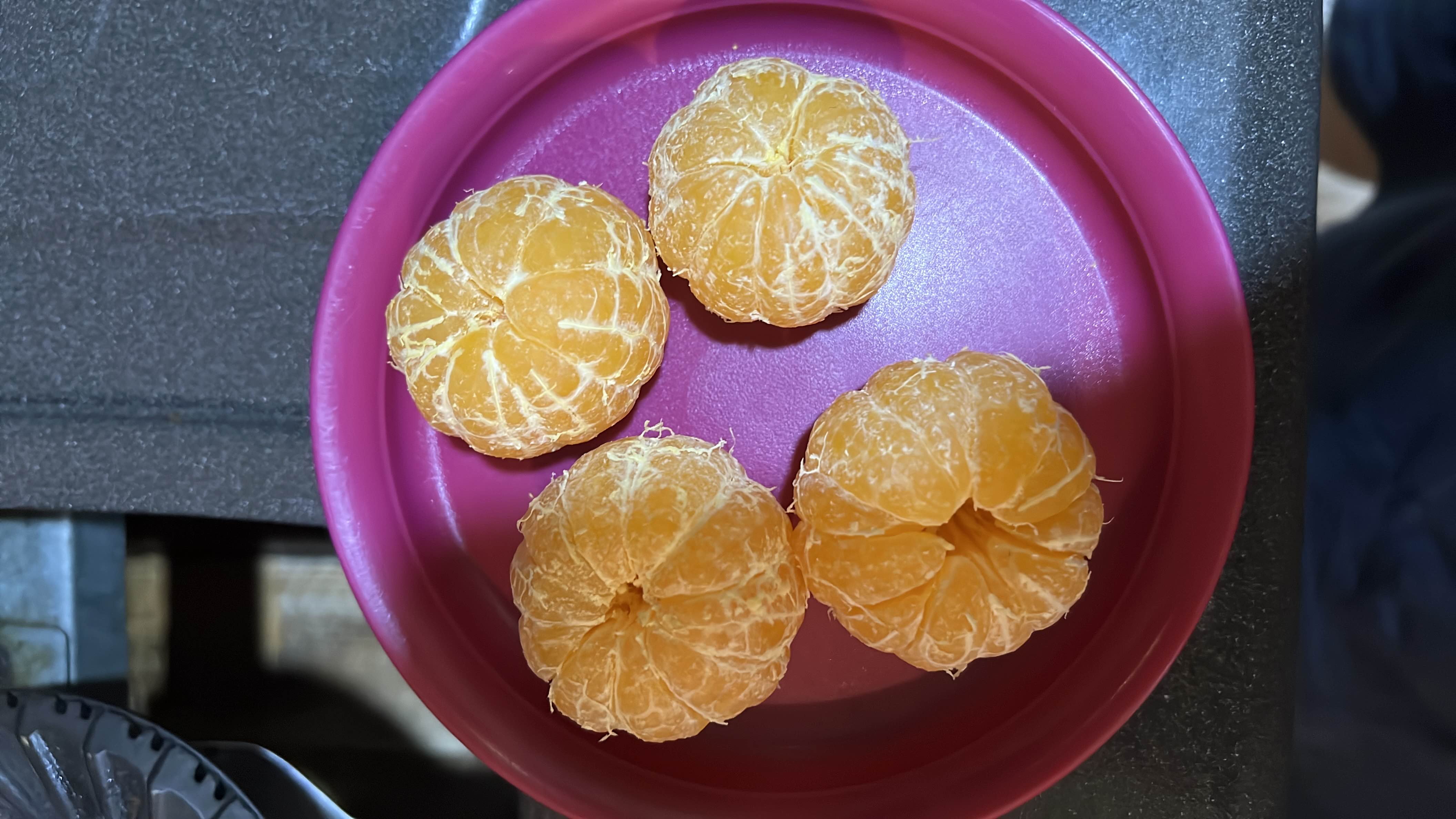 This image shows four peeled mandarin oranges on a plate. Mandarins are a low-calorie fruit rich in vitamin C, fiber, and natural sugars, making them a healthy snack option.