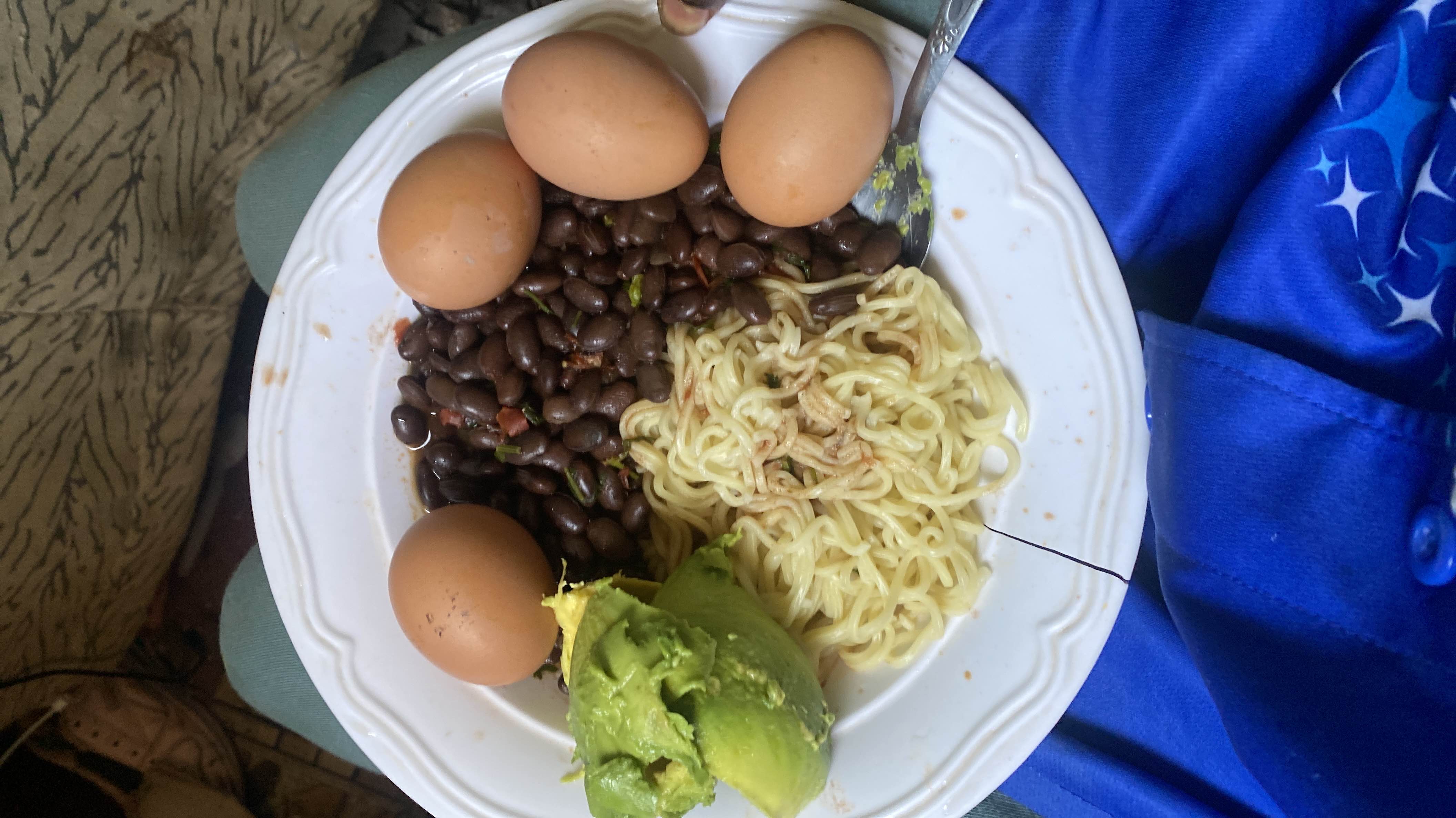 A high-protein meal consisting of boiled eggs, black beans, instant noodles, and avocado, providing a balanced mix of macronutrients.