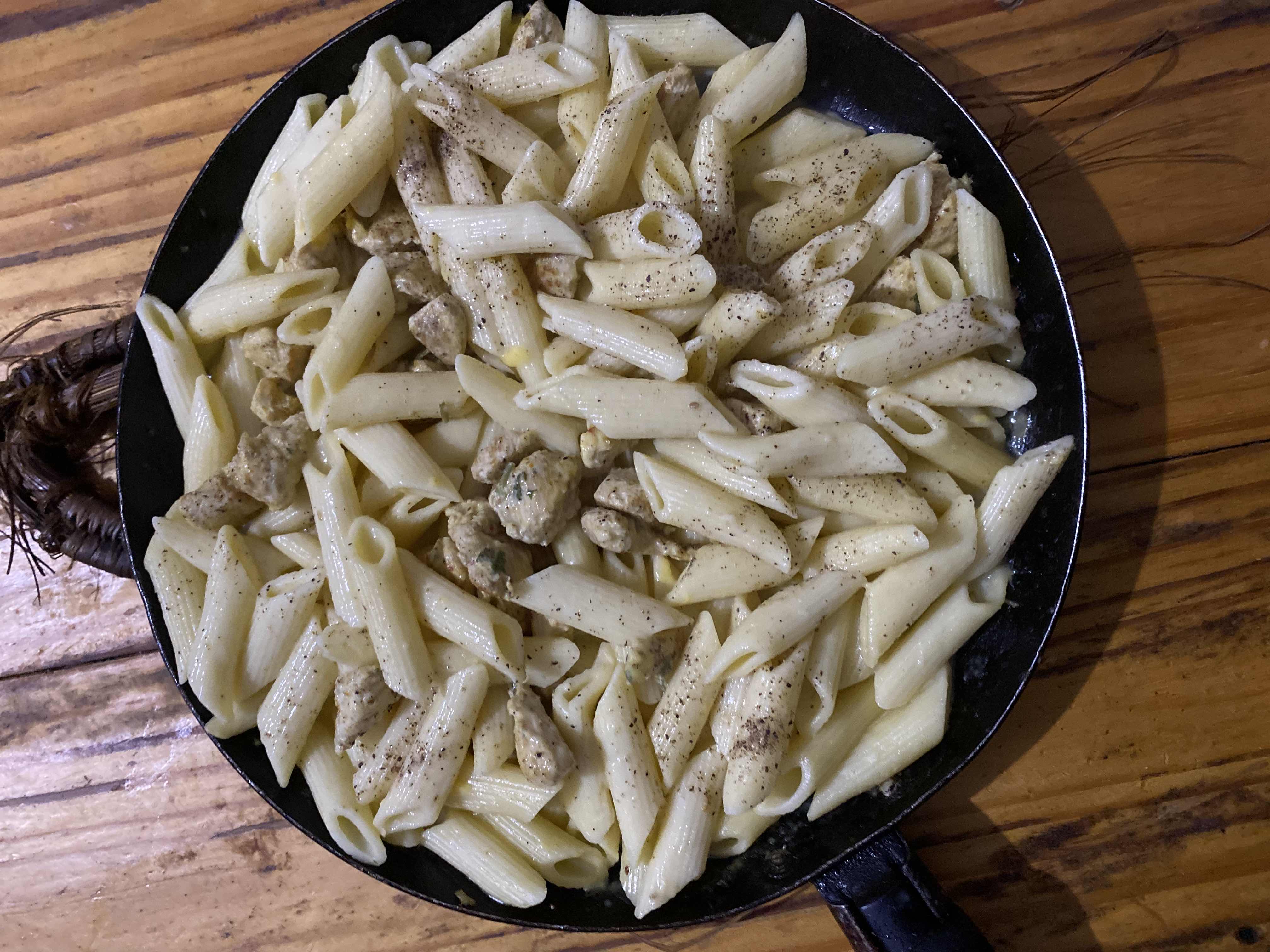Un plat de pâtes crémeuses au poulet assaisonné de poivre et d'épices.