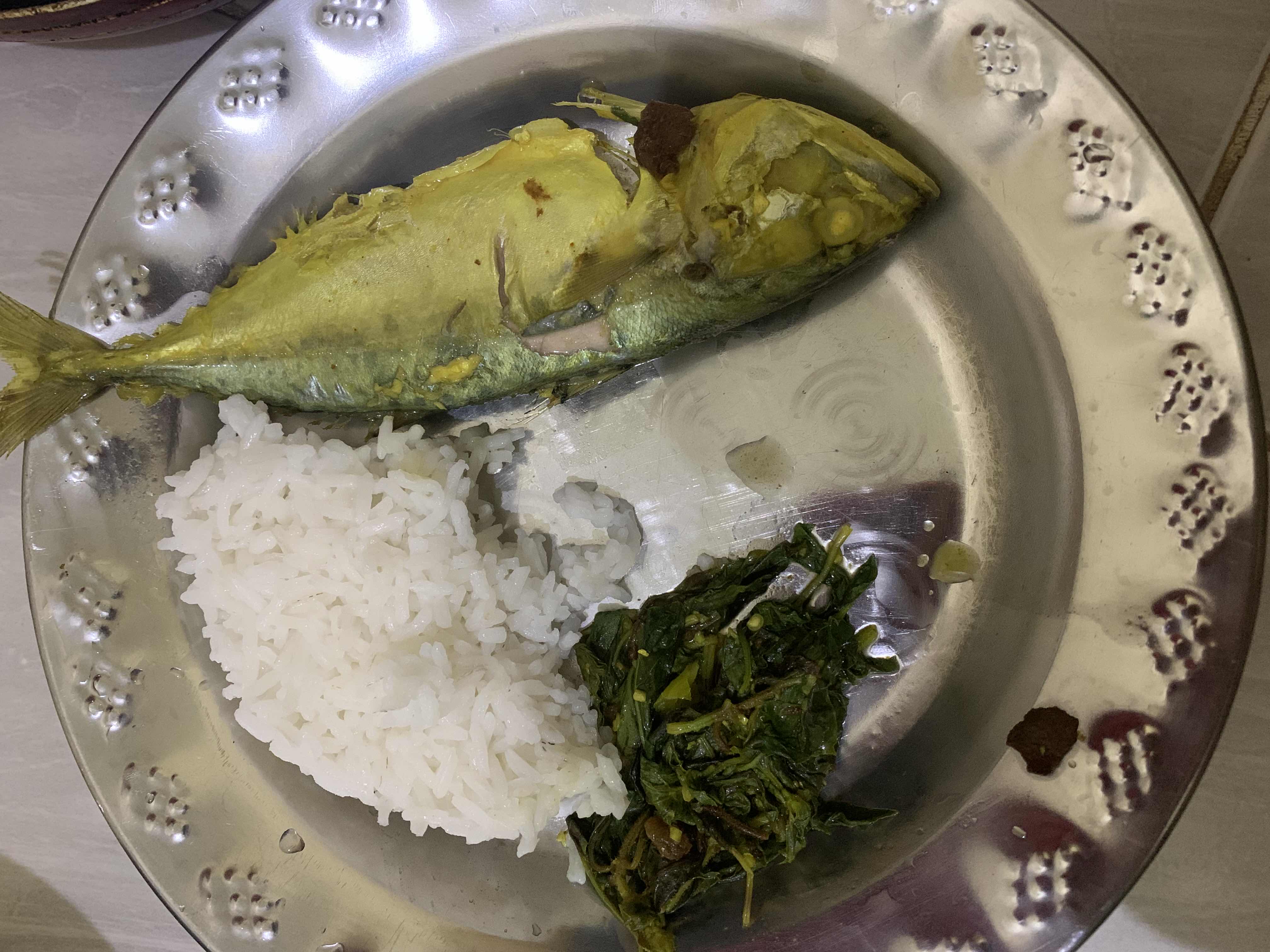 A balanced meal consisting of steamed rice, cooked fish, and sautéed leafy greens, providing a good mix of protein, carbohydrates, and essential nutrients.