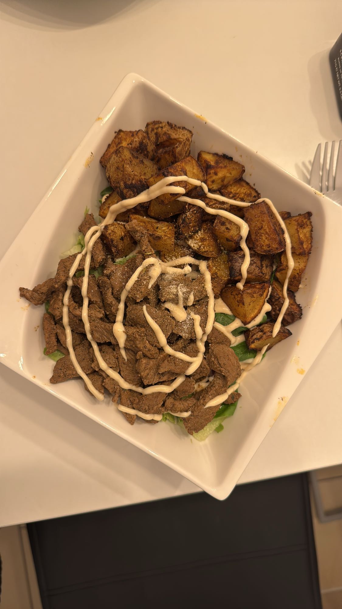Rindfleisch-Ofenkartoffel-Schüssel mit Feldsalat, Kopfsalat und roten Zwiebeln
