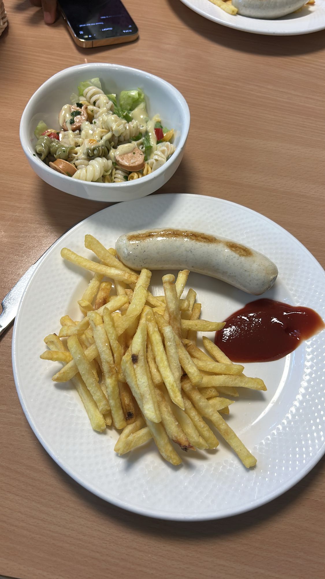 Grillwurst mit Pommes und Ketchup und mit Nudelsalat und grünes Salat