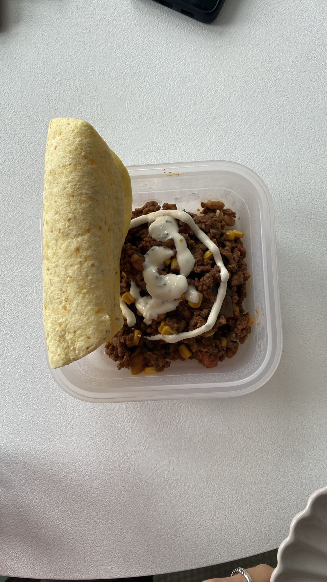 Oksekød med lidt majs og bønner, dressing og en taco brød